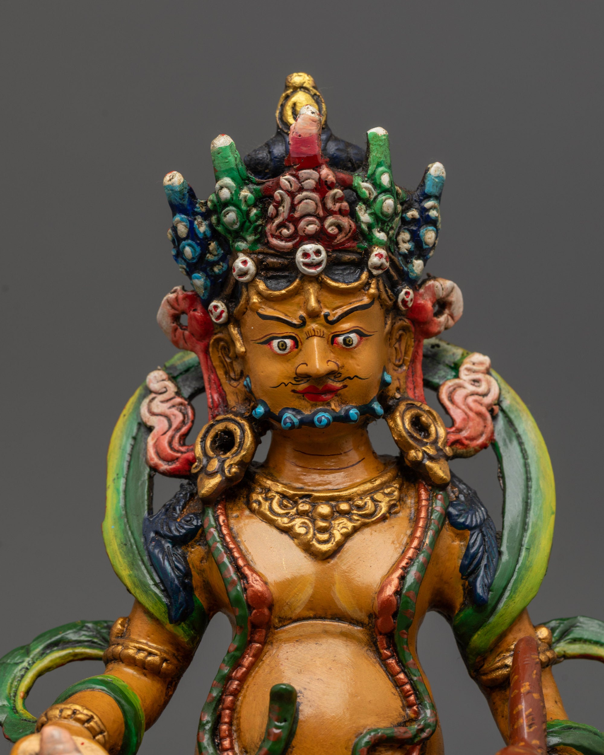 Close up of Dzambhala Statue showing semi-wrathful expression and sacred objects
