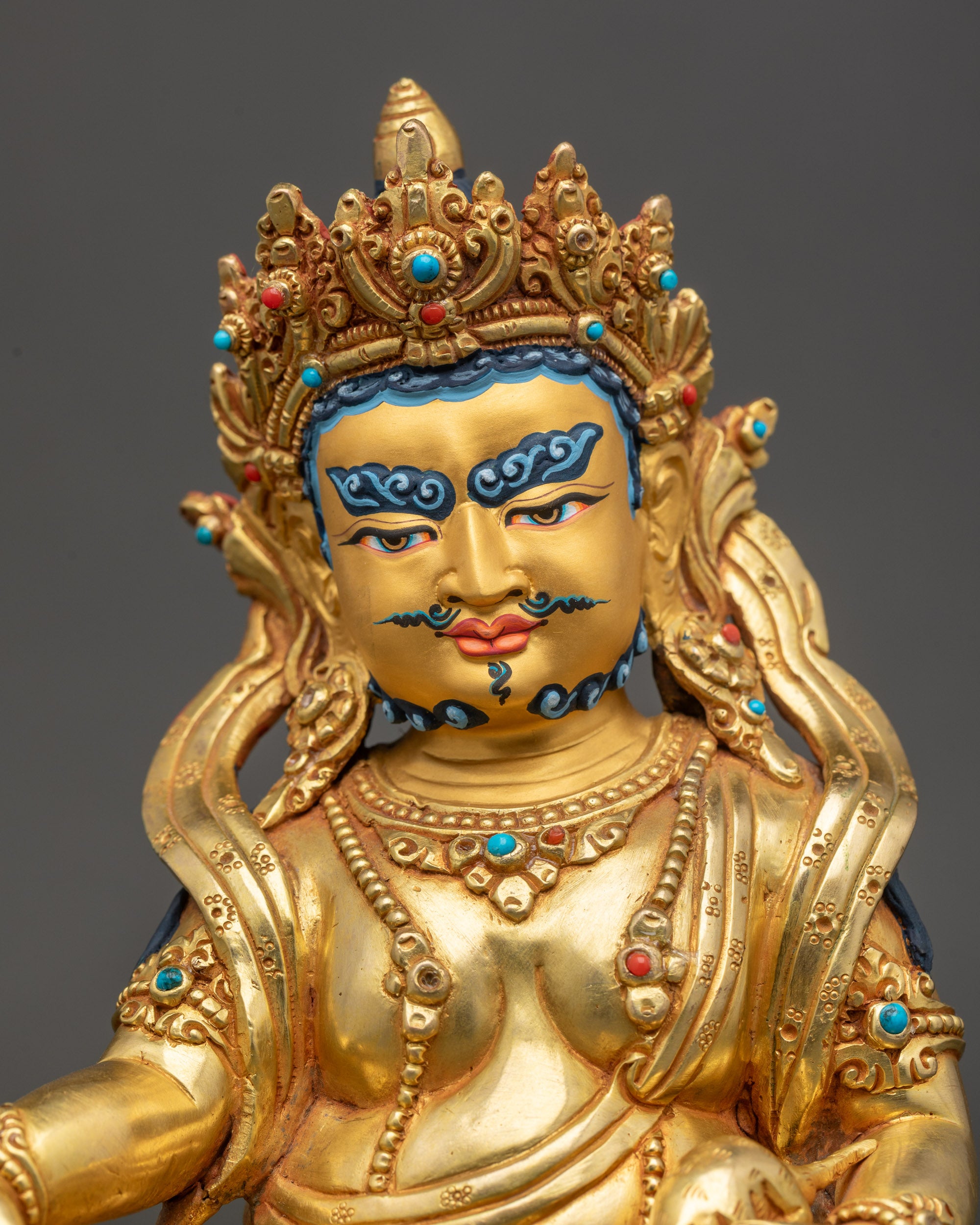 Close up of Dzambhala gold painted face with wrathful compassionate expression