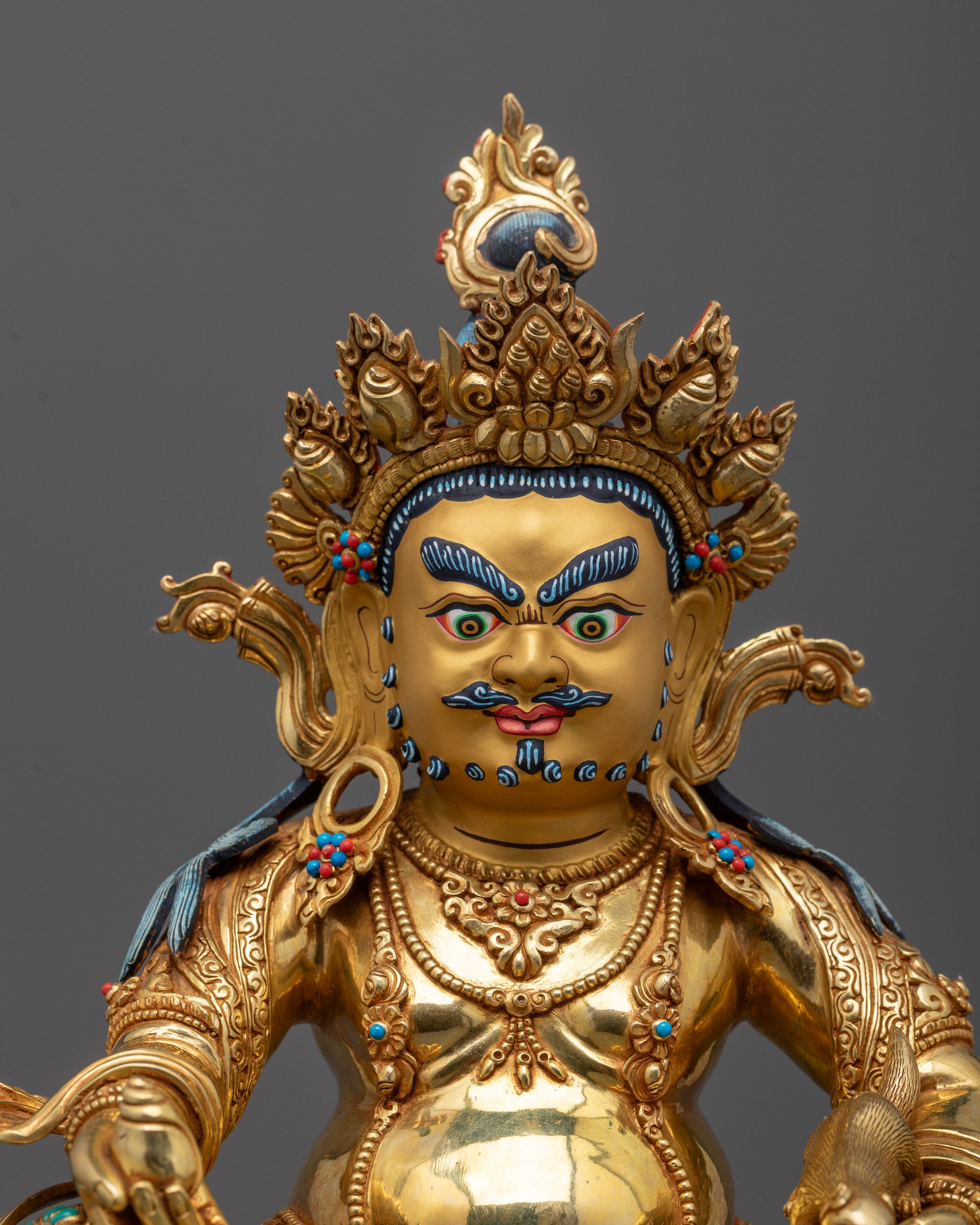 Close up of Dzambhala statue showing five-jeweled crown and jewel-spitting mongoose