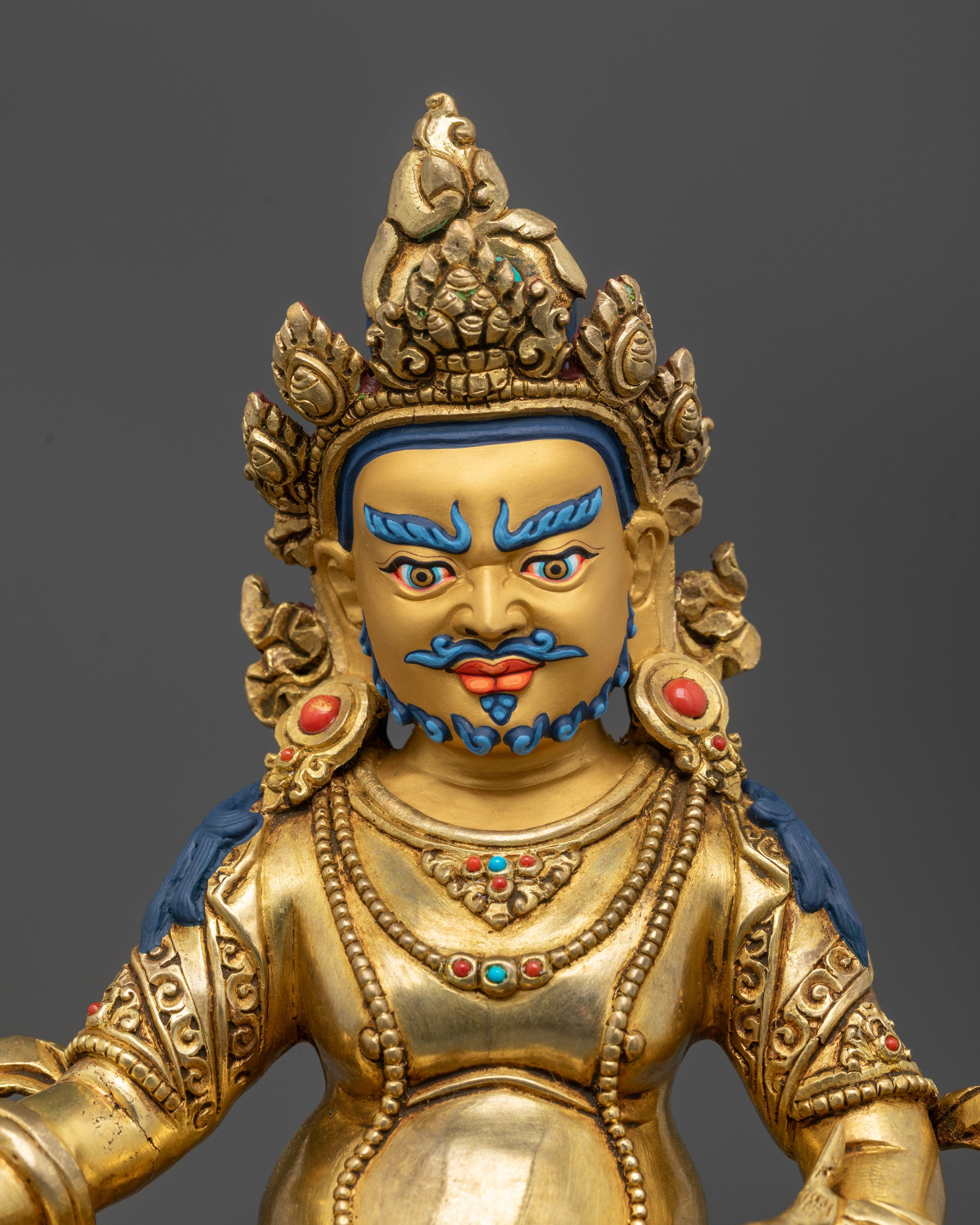 Close up of Dzambhala statue showing shell crown, semi-precious stones, and jewelry details