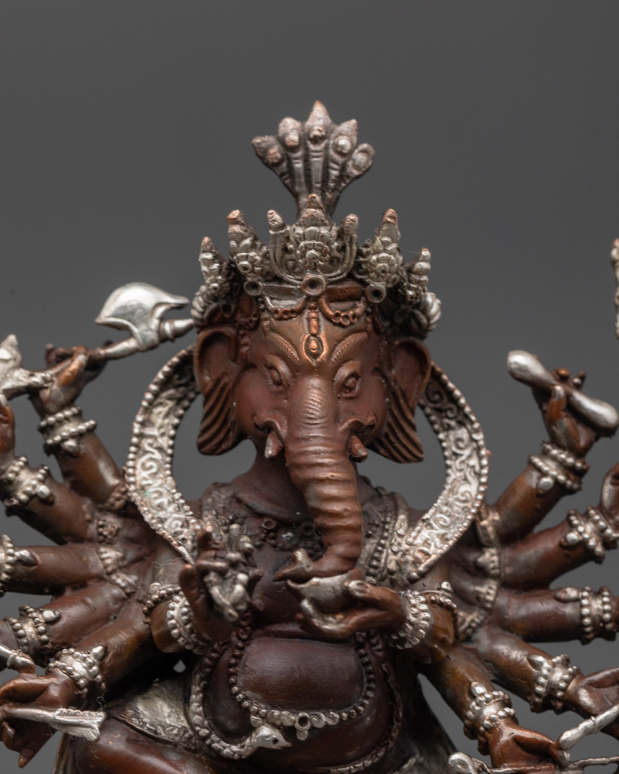 Close up of Ganesh Murti showing twelve arms holding sacred objects and third eye