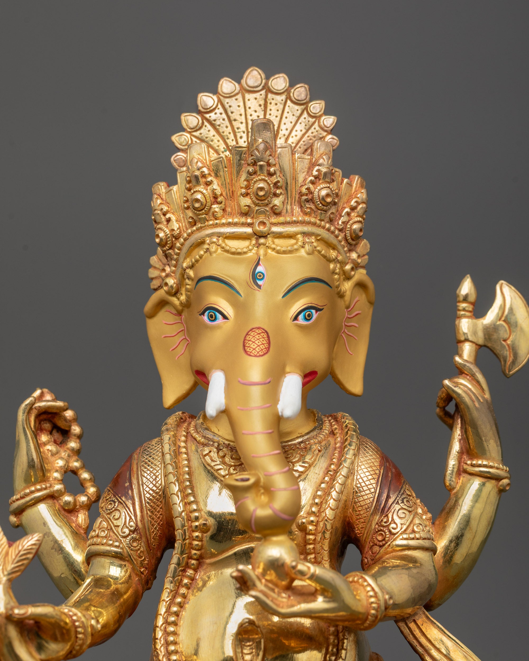 Close up of Ganesh statue’s gold fire-gilded body and detailed crown by Nepalese artisans
