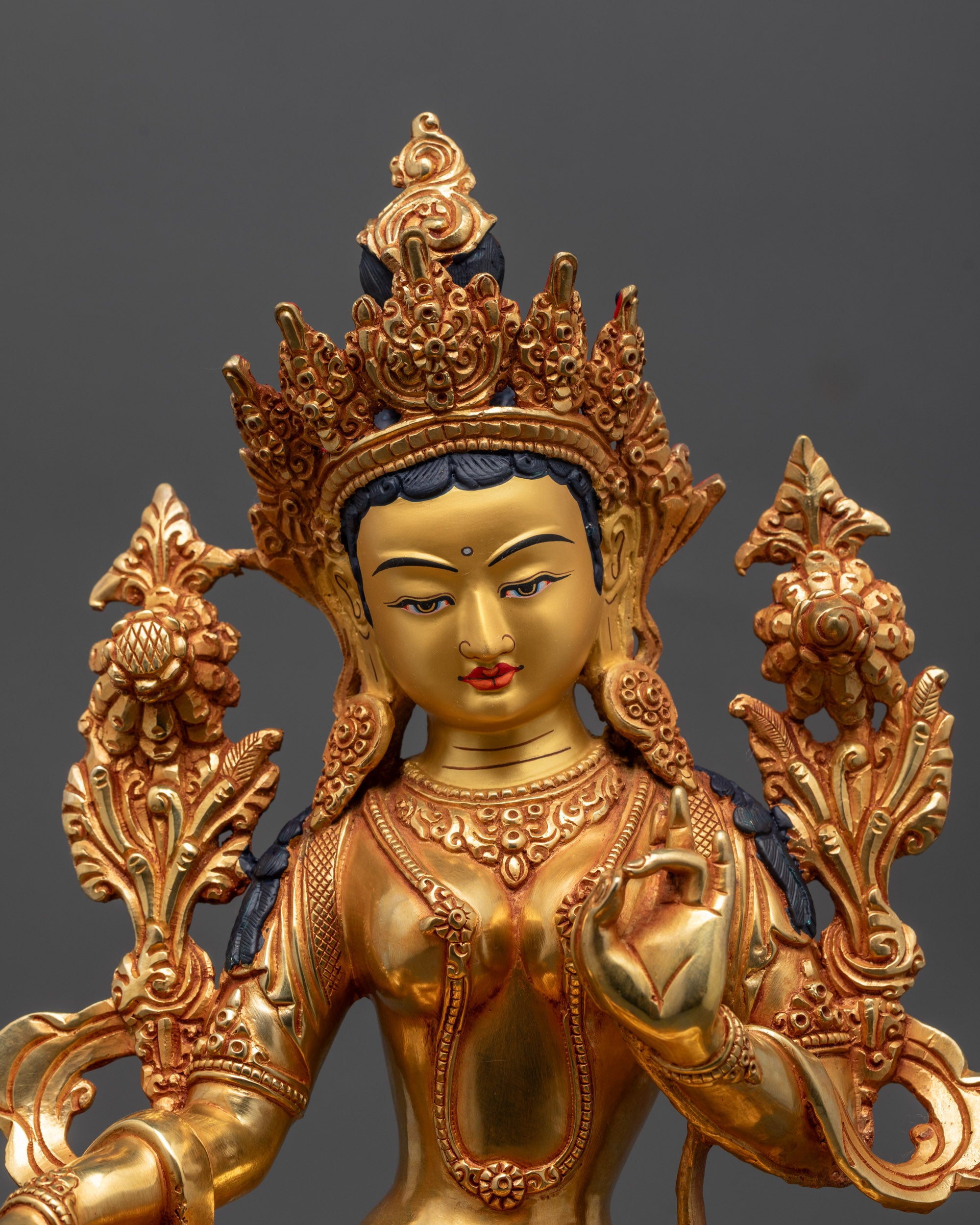Close up of Green Tara Statue showing detailed gold face and varada mudra hand gesture