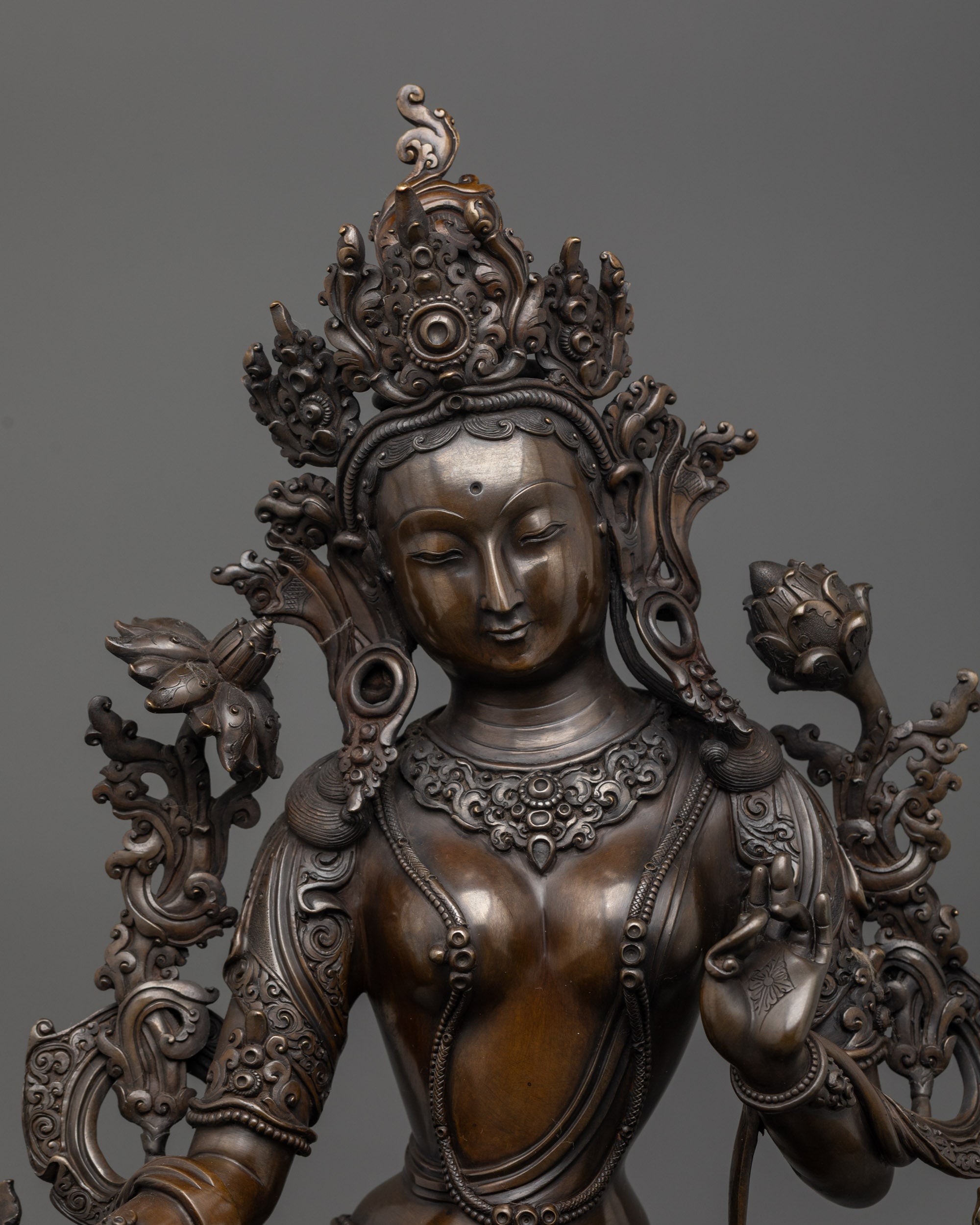 Close up of Green Tara face showing serene expression and detailed five-jeweled crown