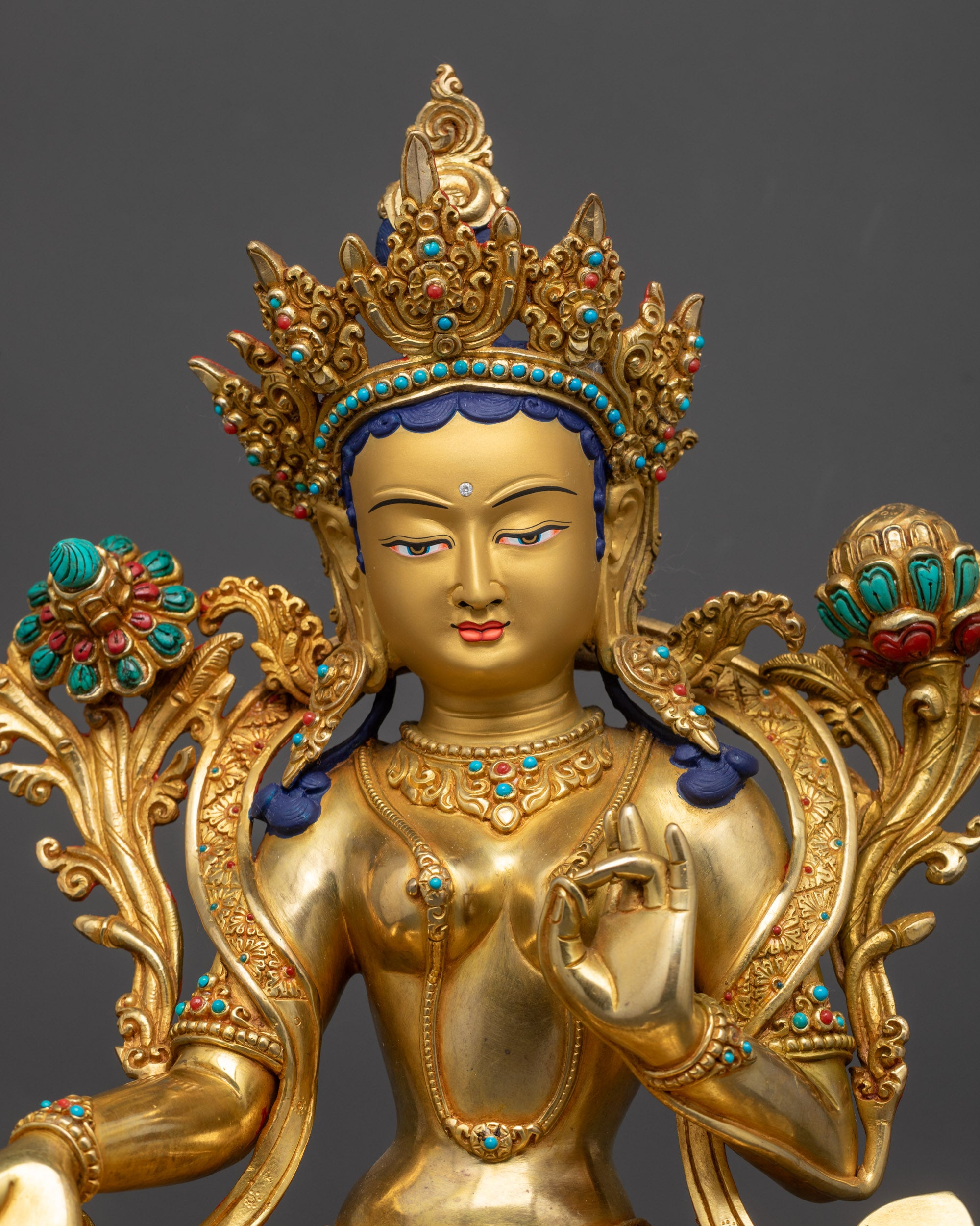 Close up of Green Tara statue face with serene expression and jeweled crown
