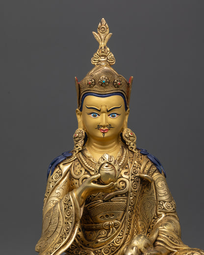 Close up of Guru Norlha’s serene gold-gilded face, lotus hat, kasaya, and gemstone details