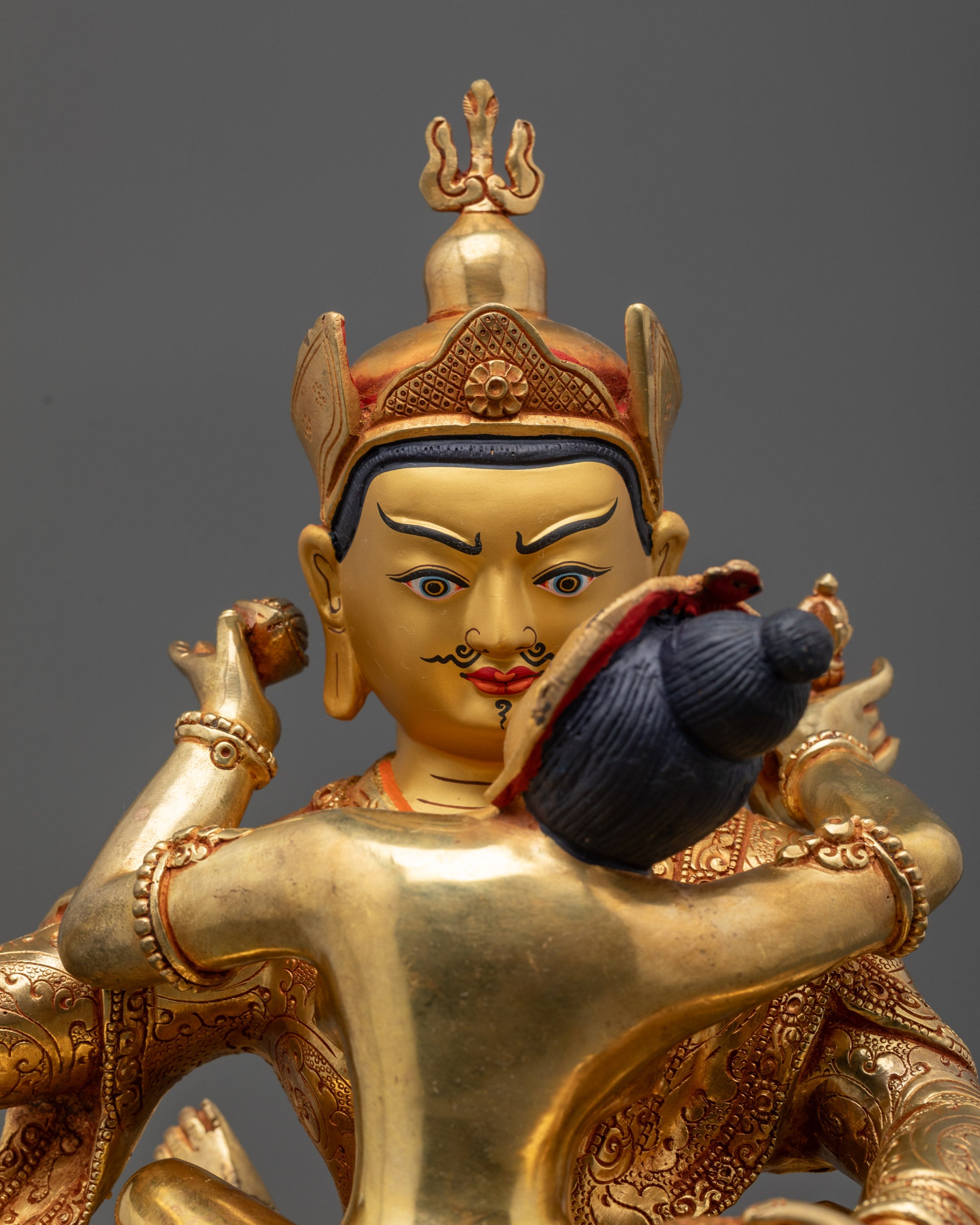 Close up of Guru Padmasambhava with semi-wrathful face holding vajra and kapala