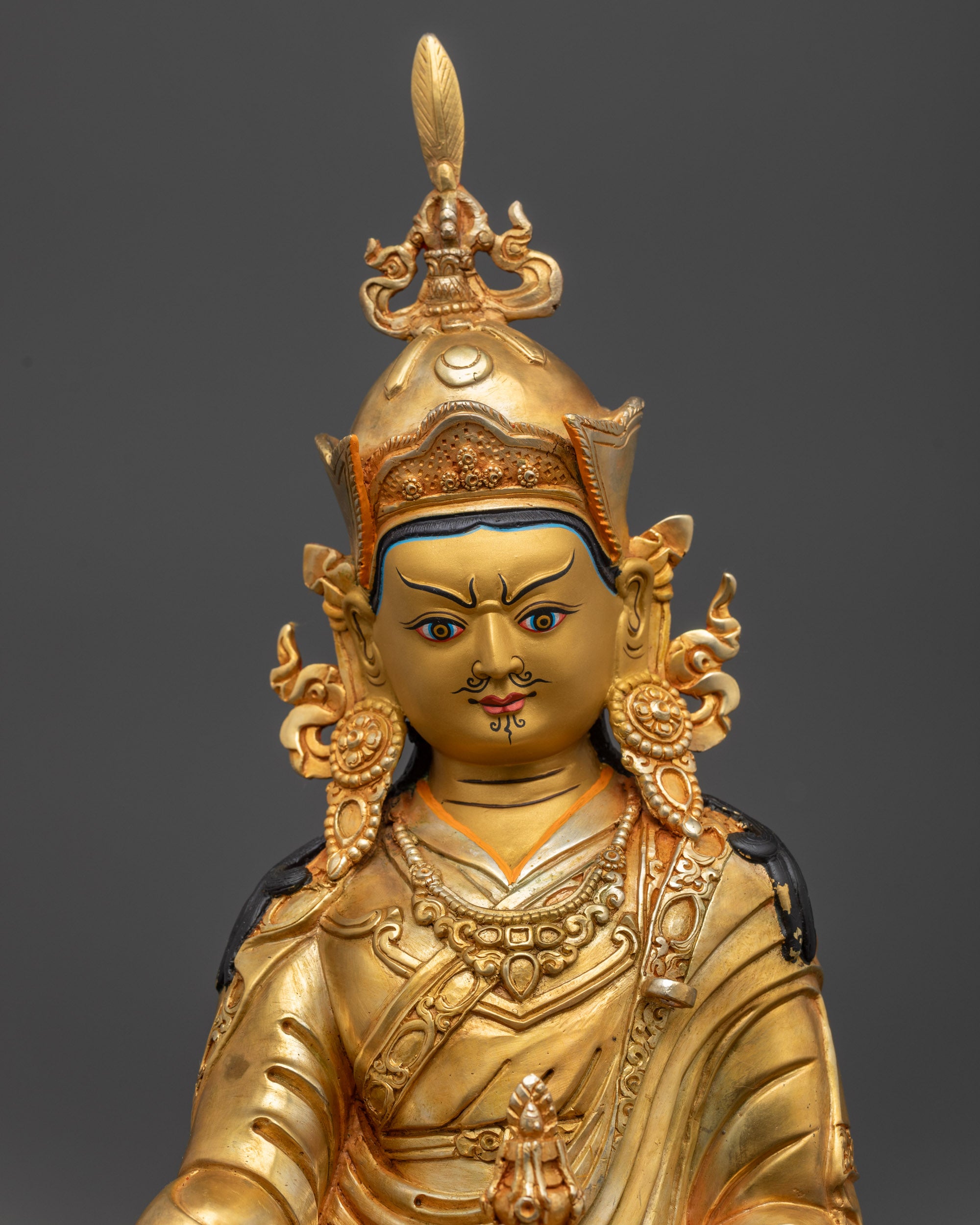 Close up of Guru Rinpoche Statue showing khatvanga trident and intricate Tripitaka robe
