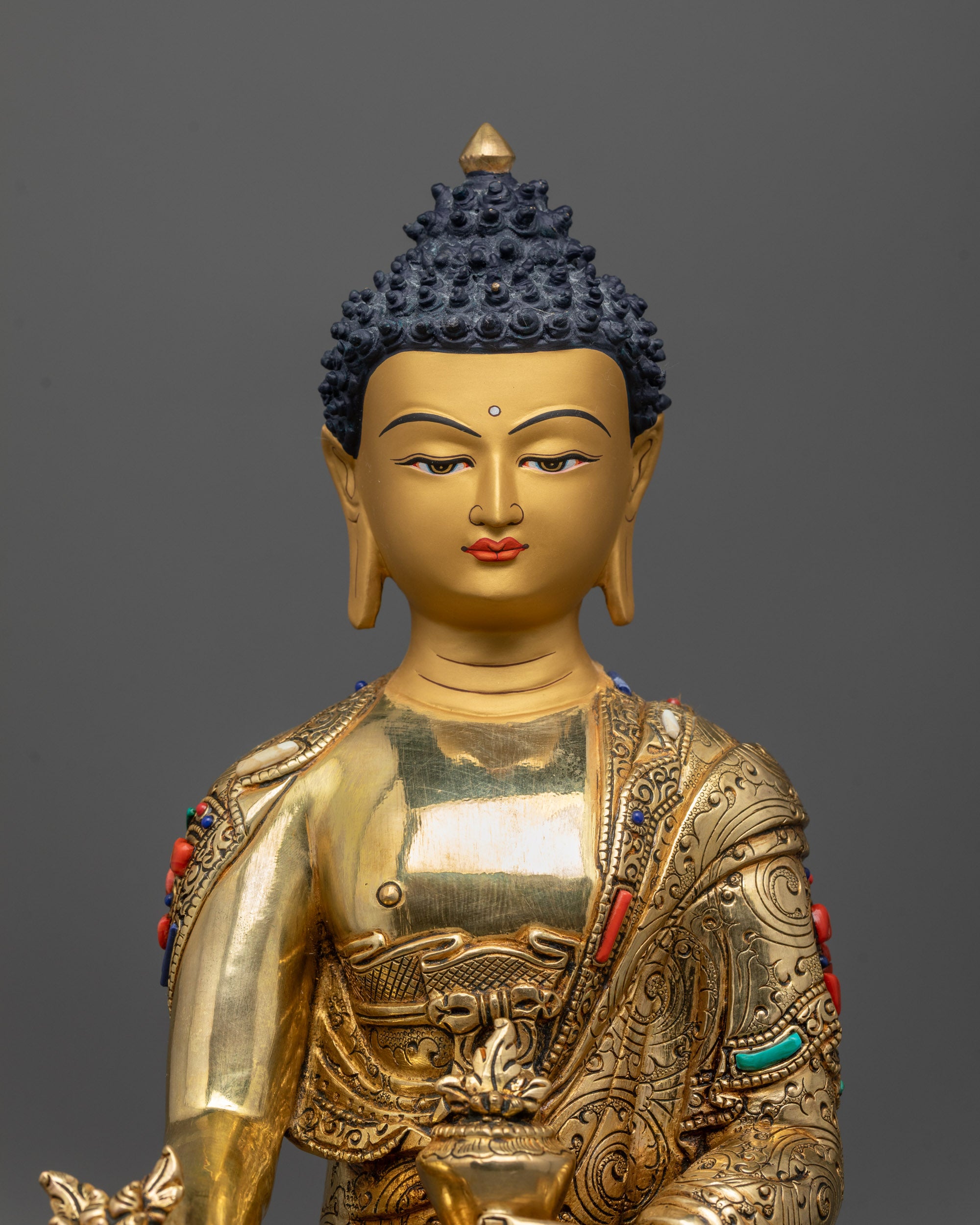 Close up of Healing Buddha statue showing intricate carved robes and detailed patterns