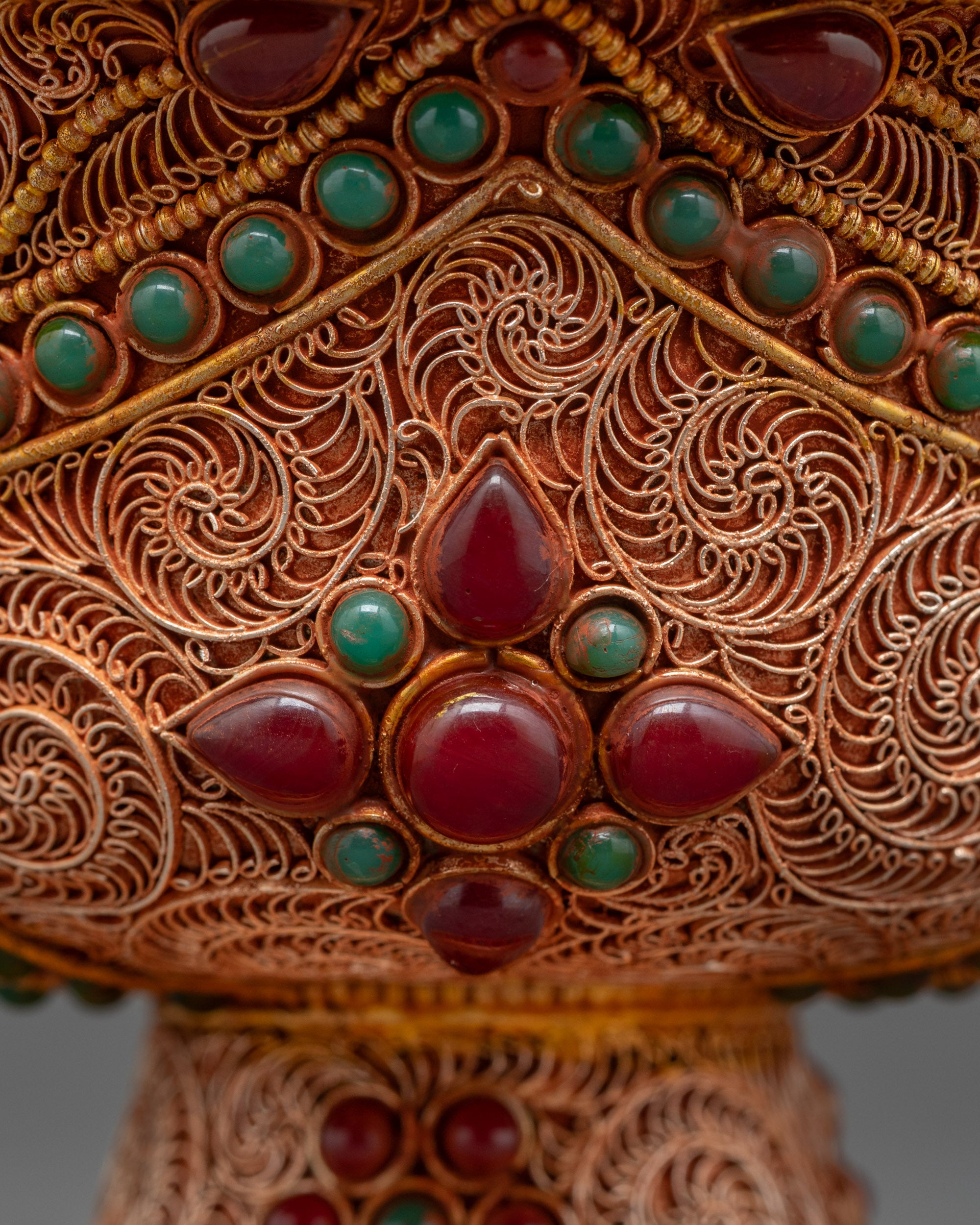 Close up of Himalayan carved Water Offering Bowl showing ruby and emerald details
