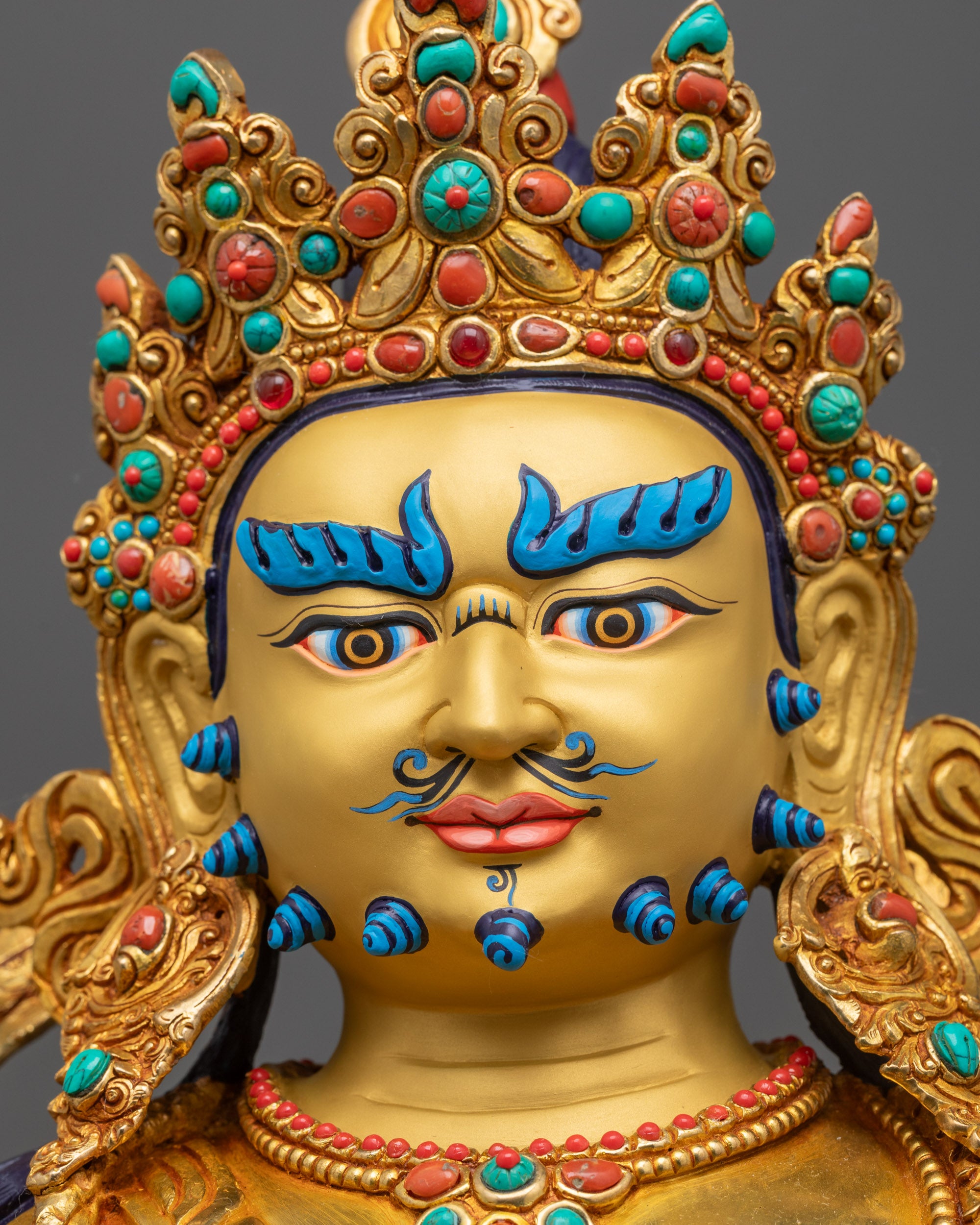 Close up of Jambhala Statue with radiant gold-gilded face and crown