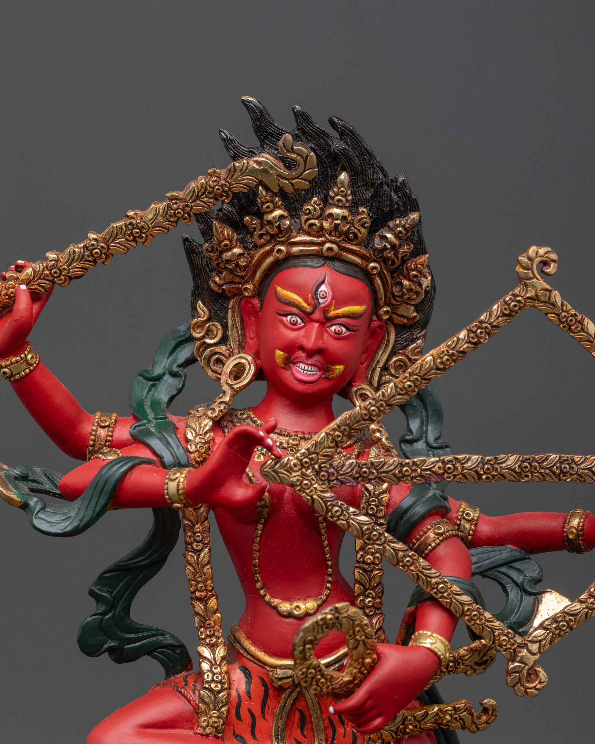 Close up of Kurukulla Statue showing red body, third eyes, and gold-plated flower bow