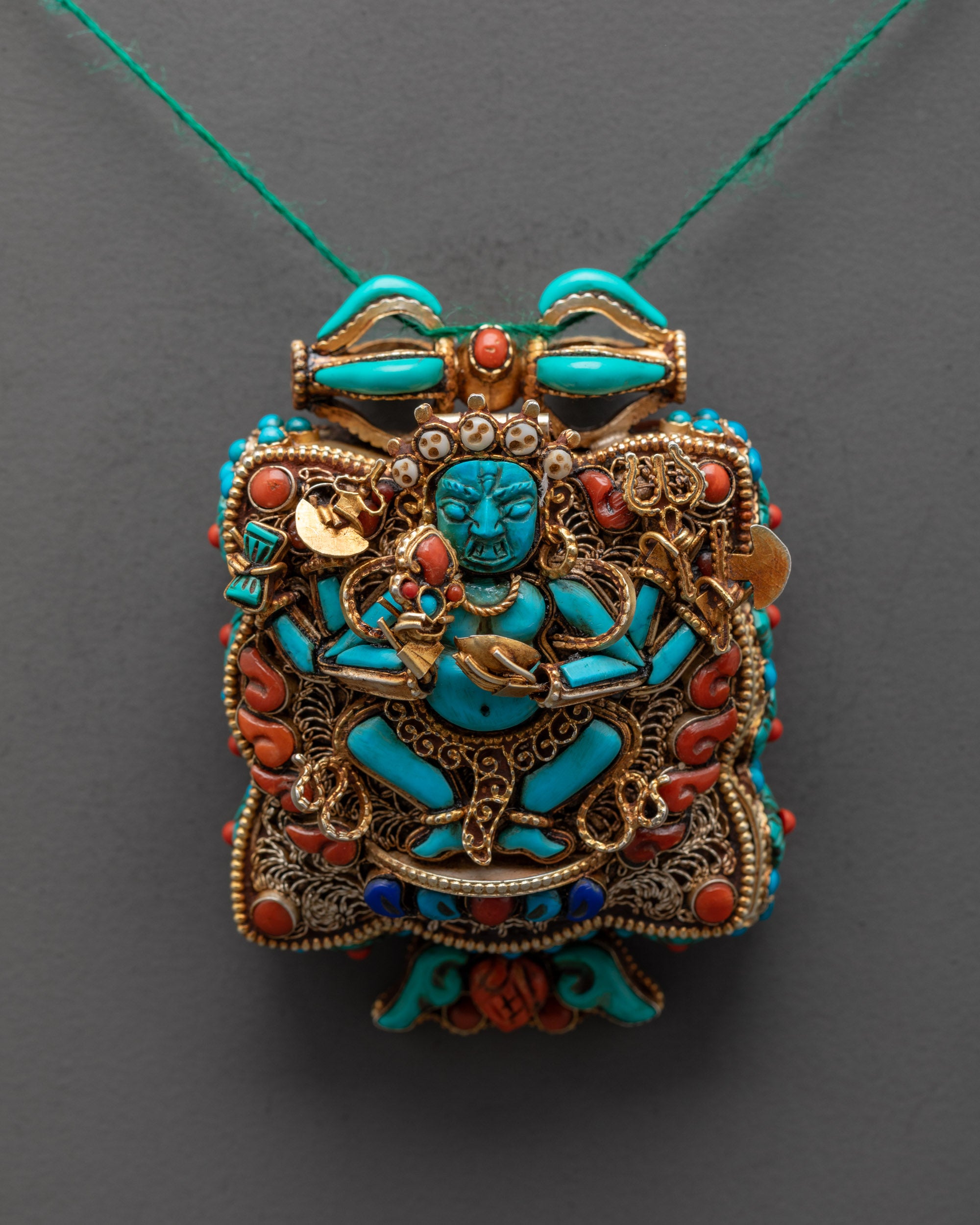 Close up of Mahakala Praying Box Locket showing turquoise figure and semi-precious stones detail