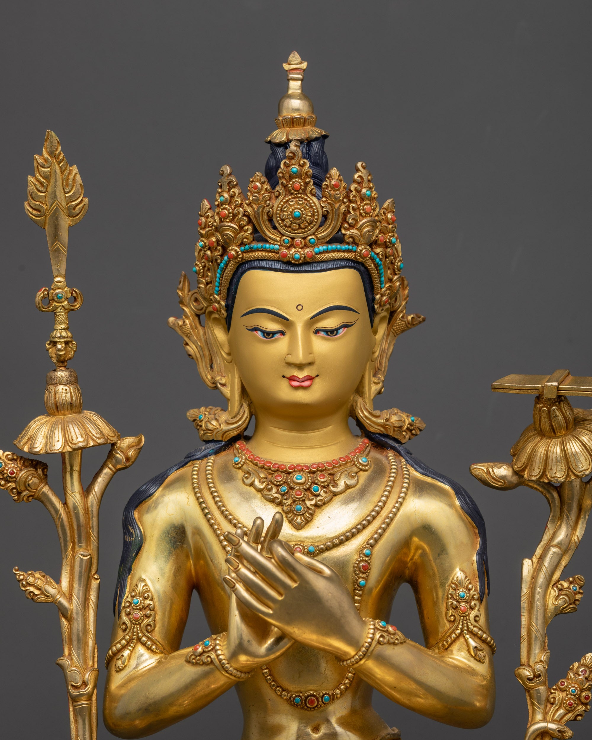 Close up of Manjushri’s serene gold-gilded face and intricately carved floral garment
