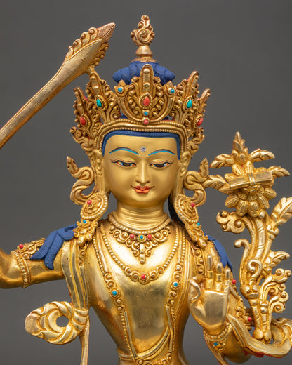 Close up of Manjushri statue showing gold-gilded face and intricate robe details
