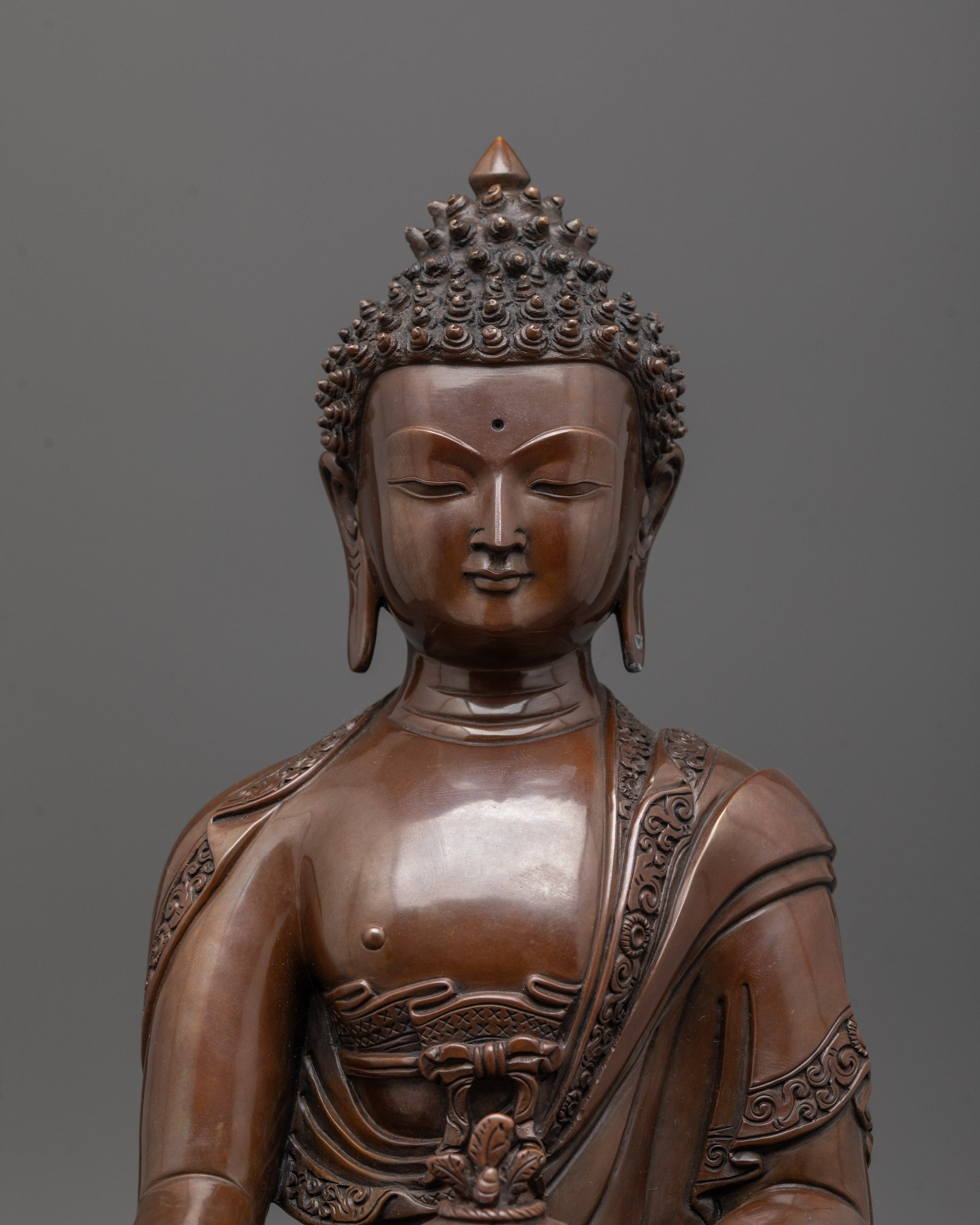 Close up of Medicine Buddha face showing oxidized copper finish and serene healing expression