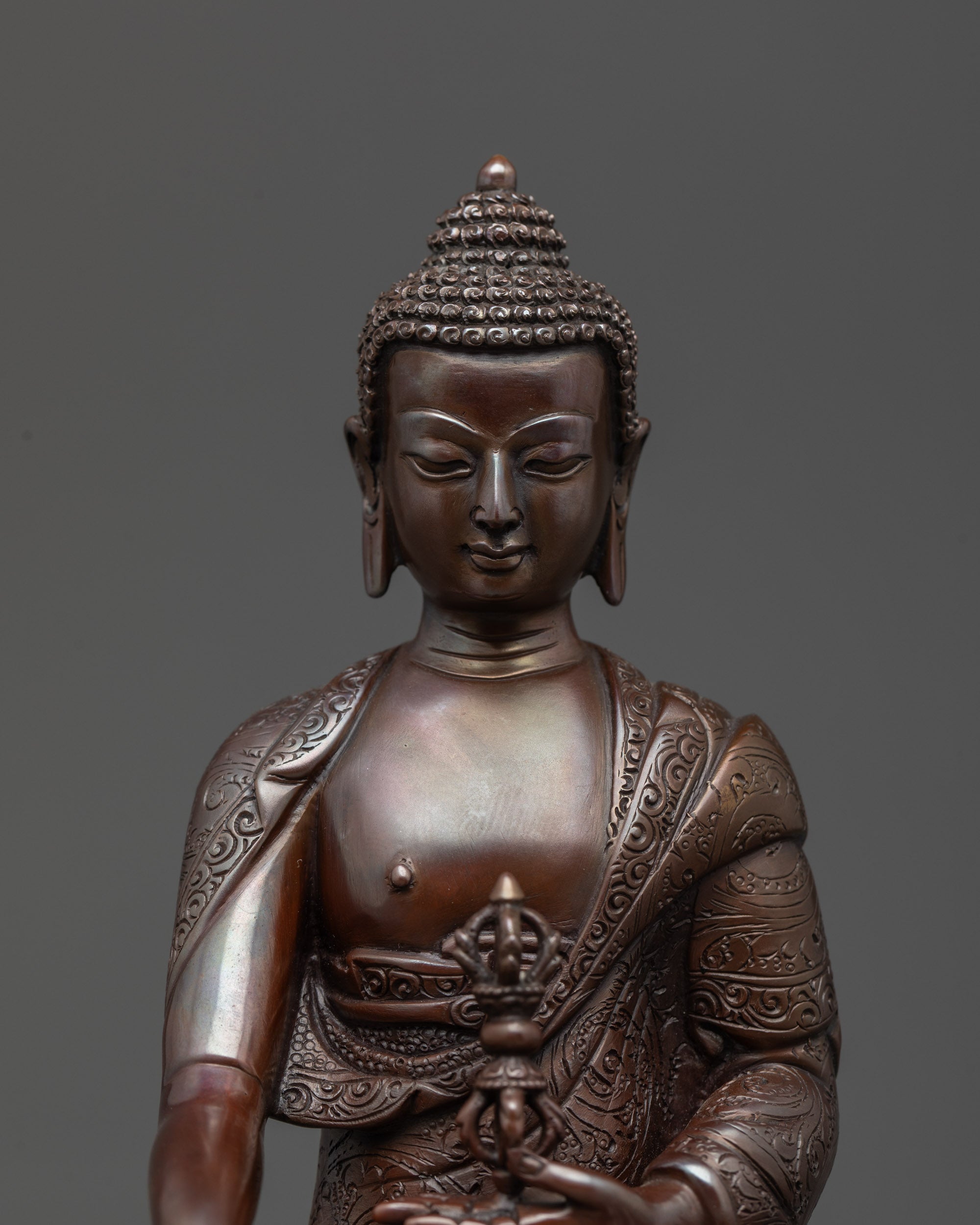 Close up of Mitrugpa Buddha’s face and intricate carvings on oxidized copper statue