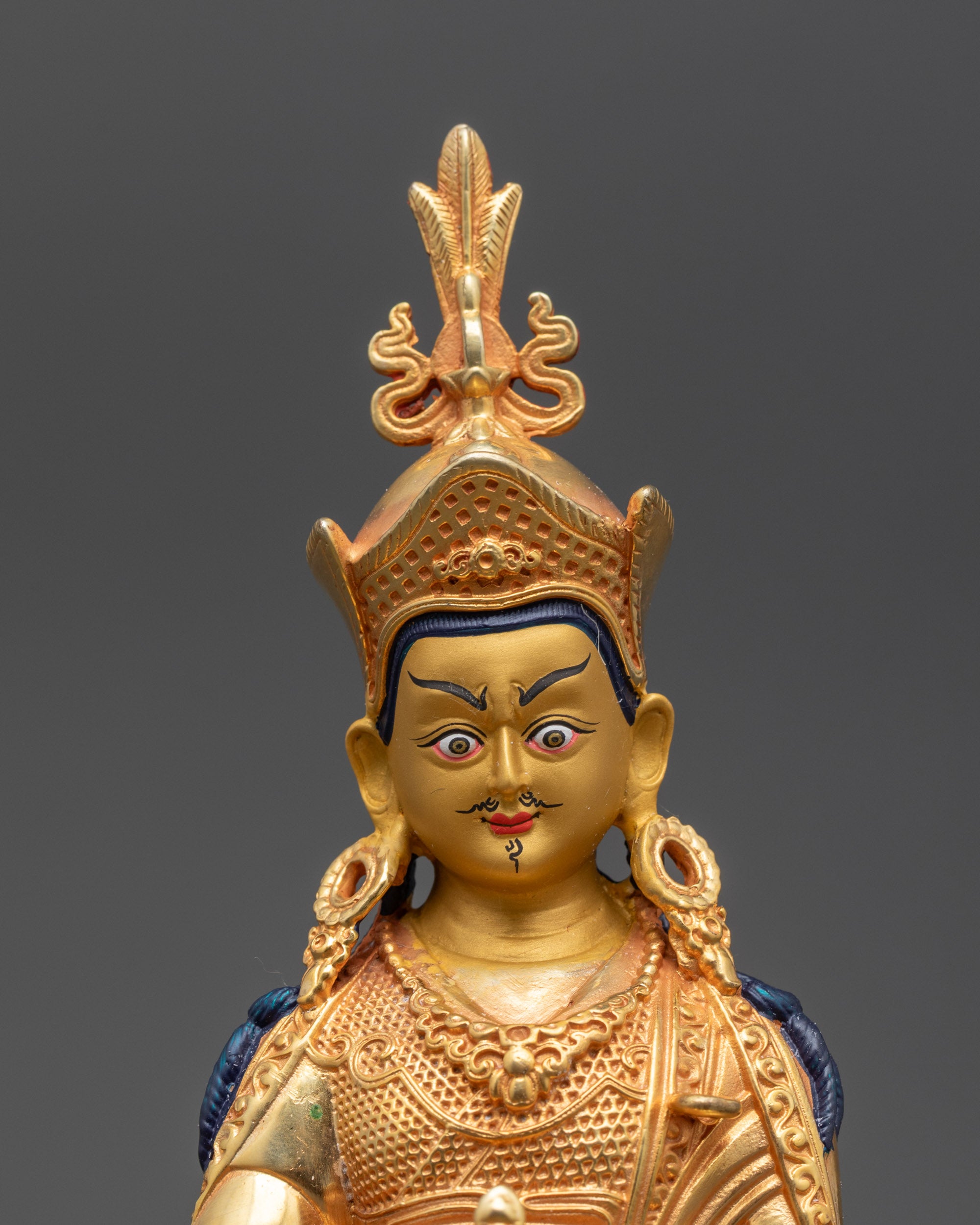 Close up of Padmasambhava sculpture showing gold-gilded face and lotus hat