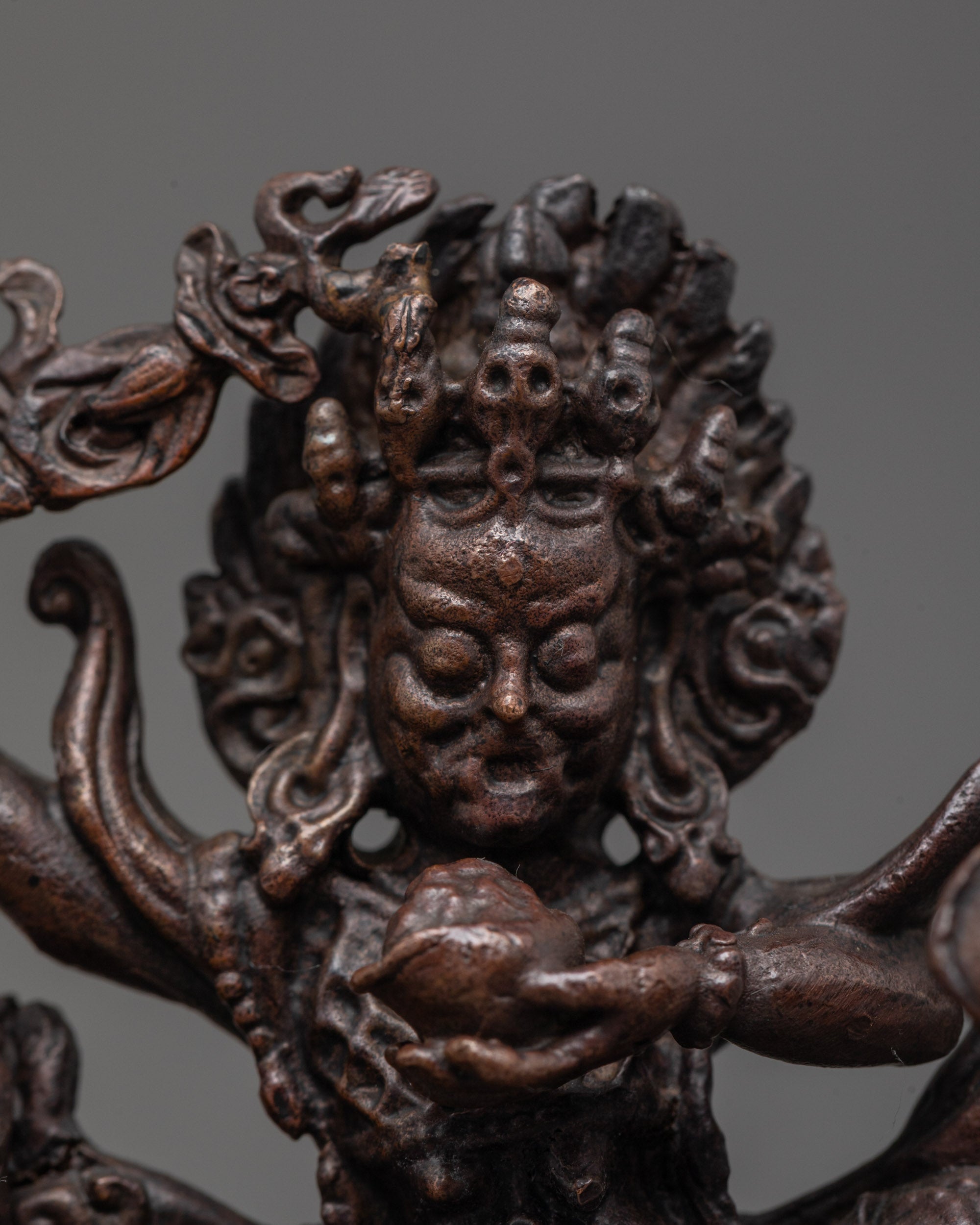 Close up of Palden Lhamo’s skull crown and intricate halo carvings in oxidized copper
