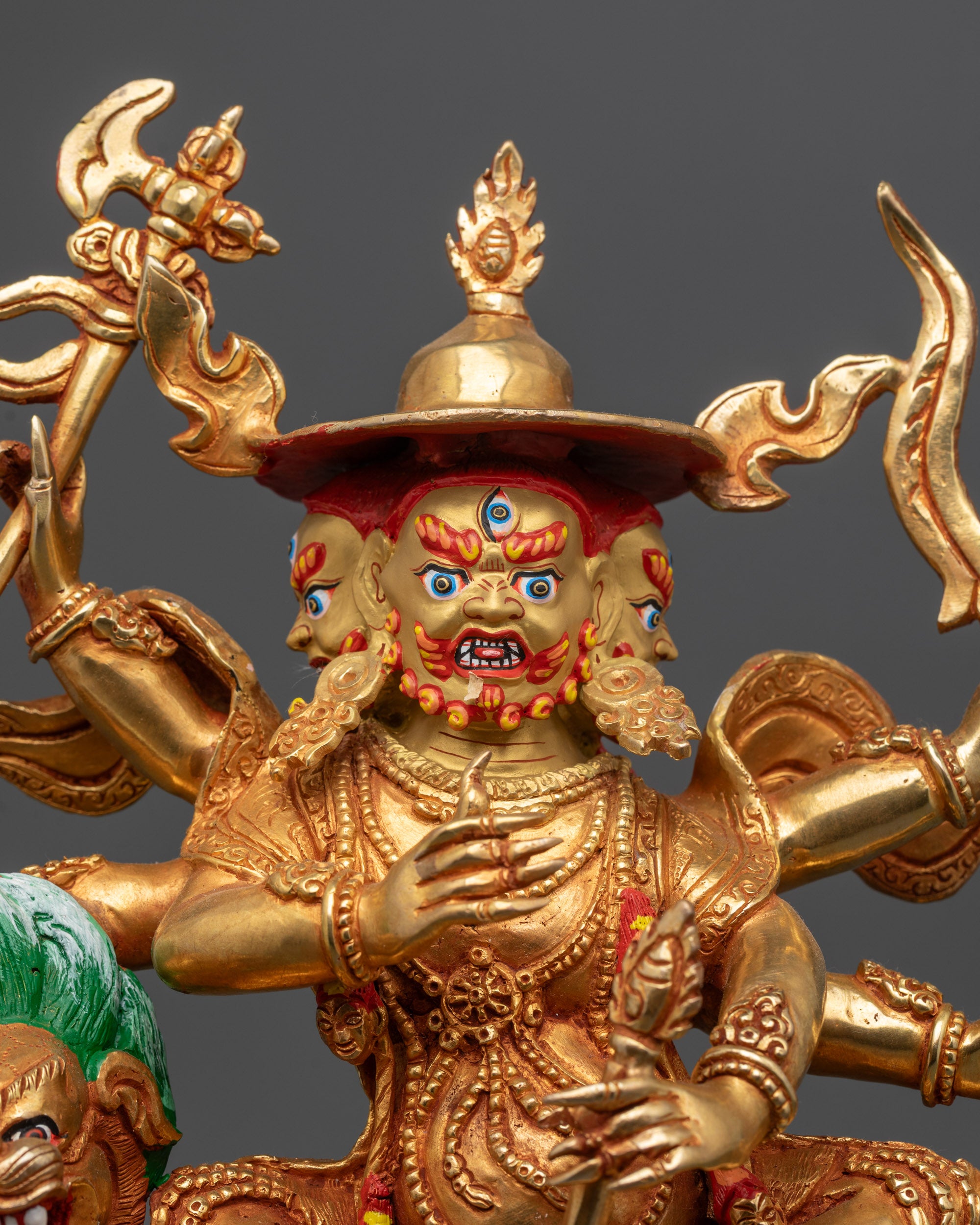 Close up of Pehar Gyalpo statue showing intricate details and six arms with weapons
