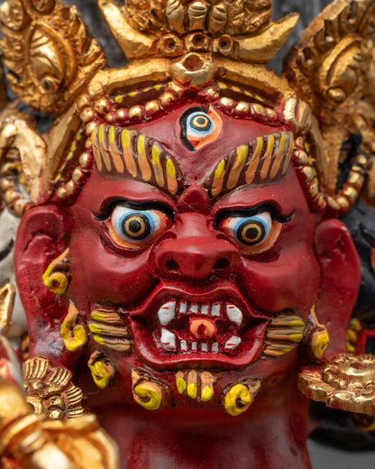 Close up of Red Dzambhala face showing wrathful expression and detailed gold jewelry
