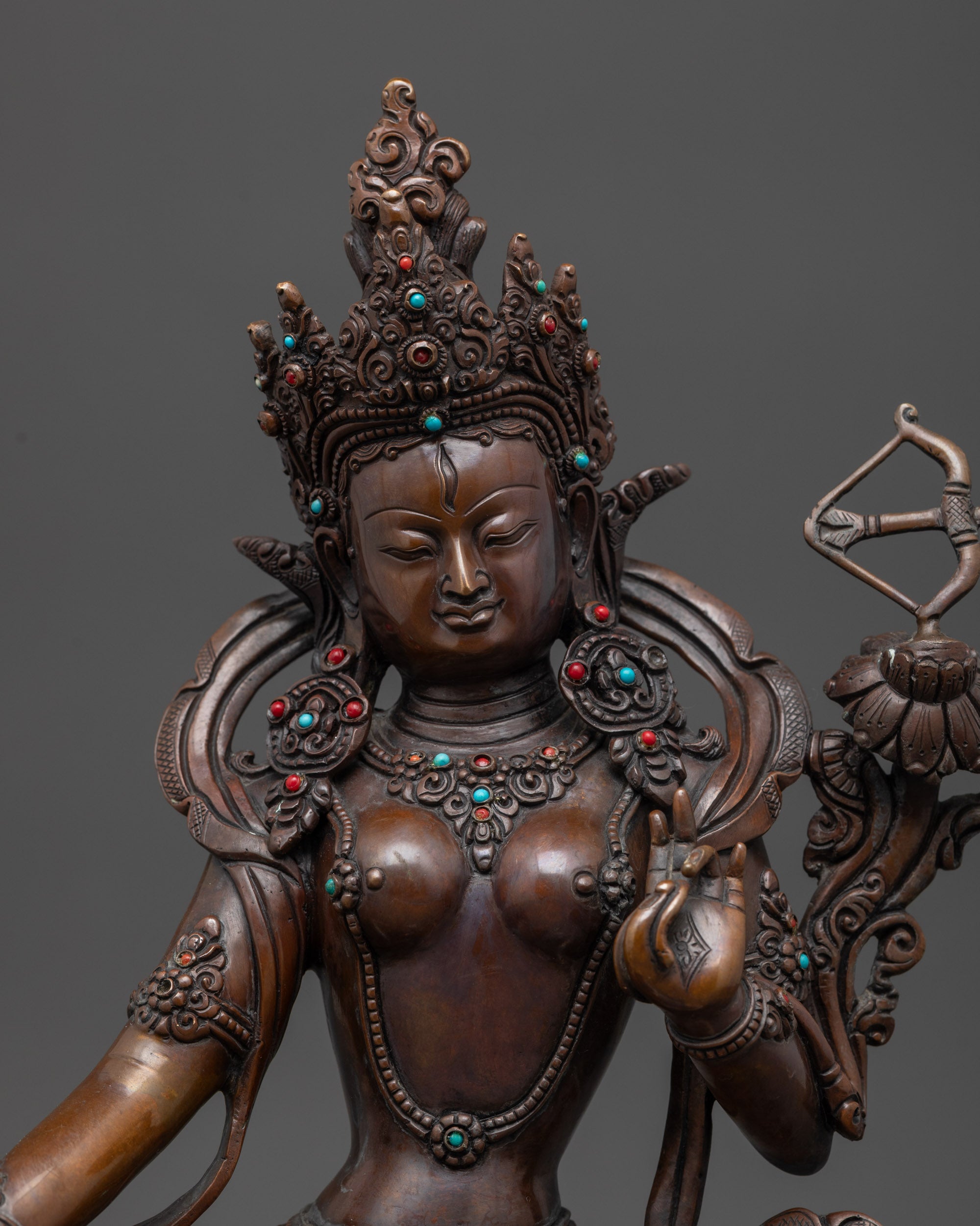 Close up of Red Tara holding utpala stem and vase, flower with bow and arrow beside shoulder