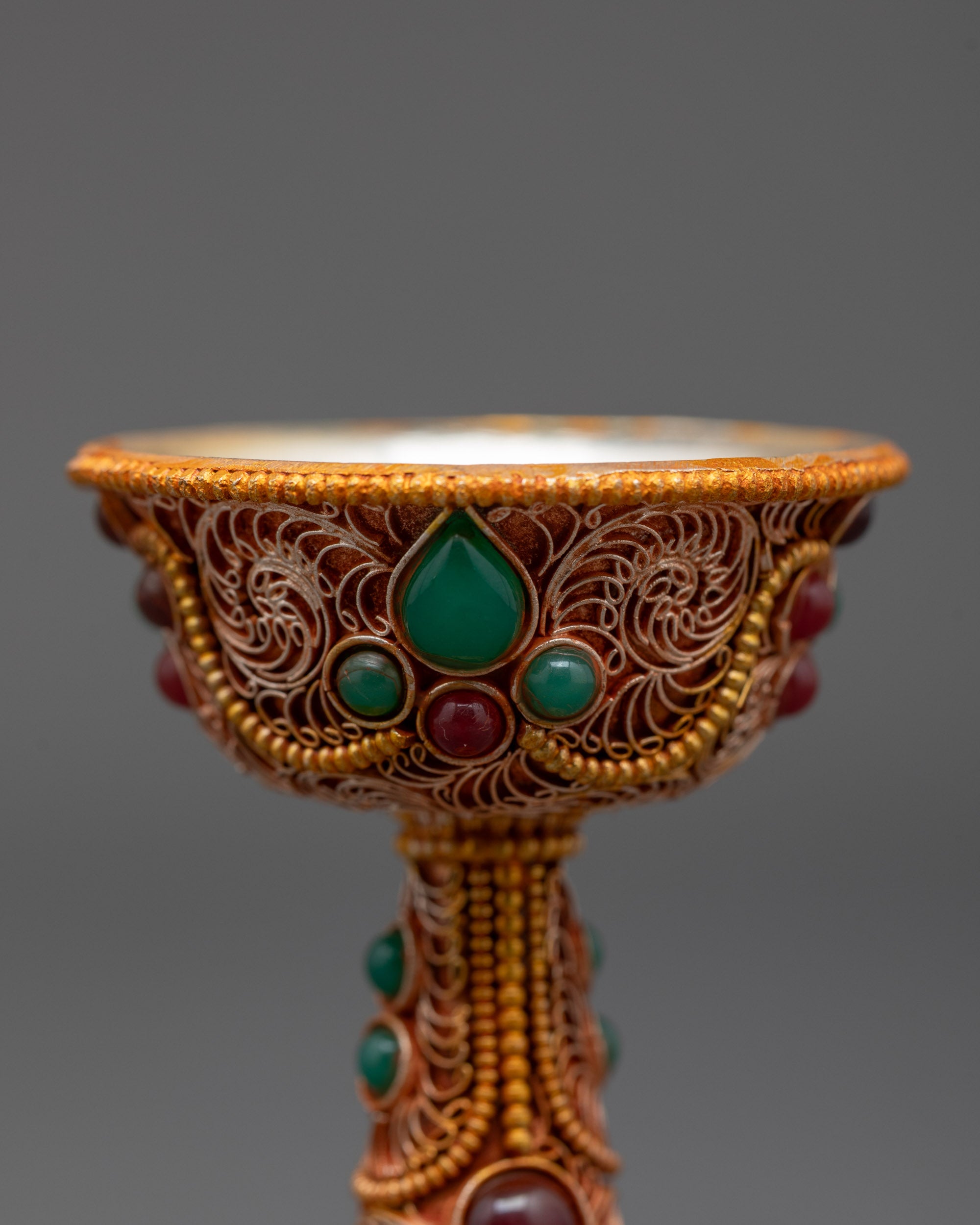 Close up of Serkyem Offering Bowl showing emerald and ruby gemstones and intricate carvings