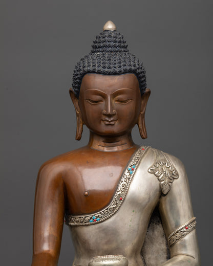 Close up of Shakyamuni Buddha holding patra bowl with silver-plated robe and stones
