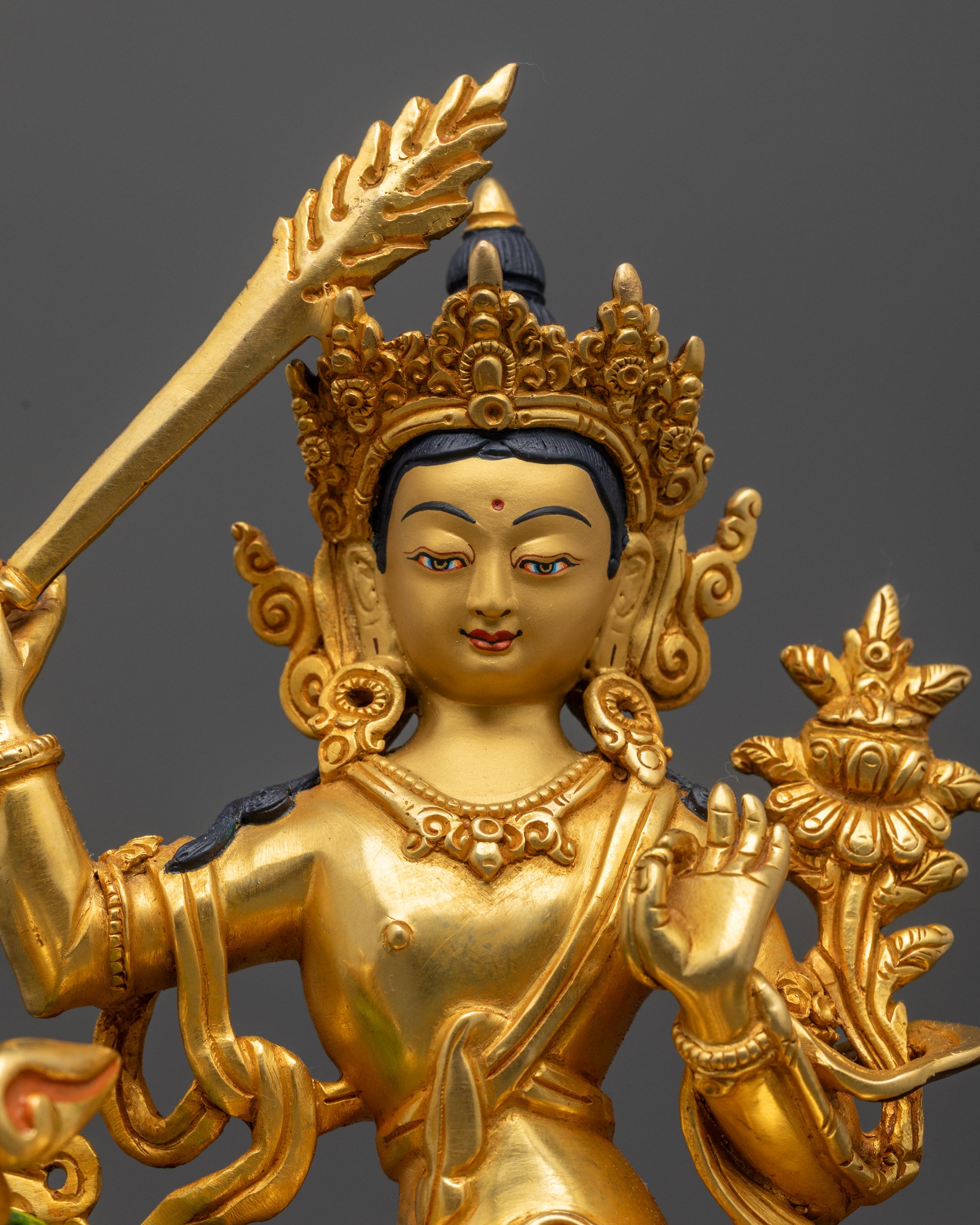 Close up of Simhada Manjushri’s crown, halo, and intricate carvings in gold over copper