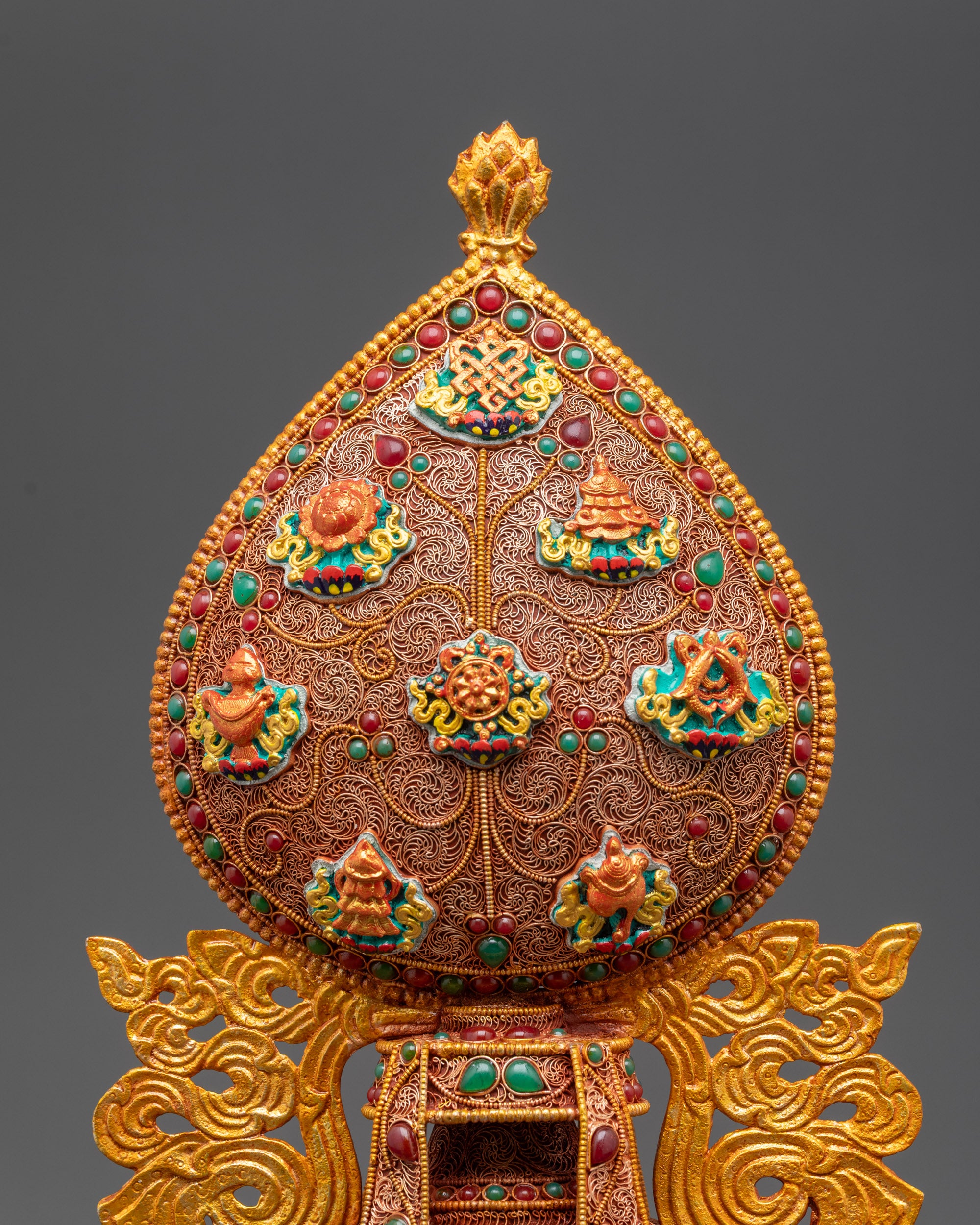 Close up of Tibetan Ashtamangala showing intricate gold filigree and semi-precious stones
