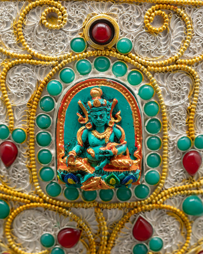 Close up of Tibetan rice pot showing Dzambhala carving with ruby turquoise emerald gems