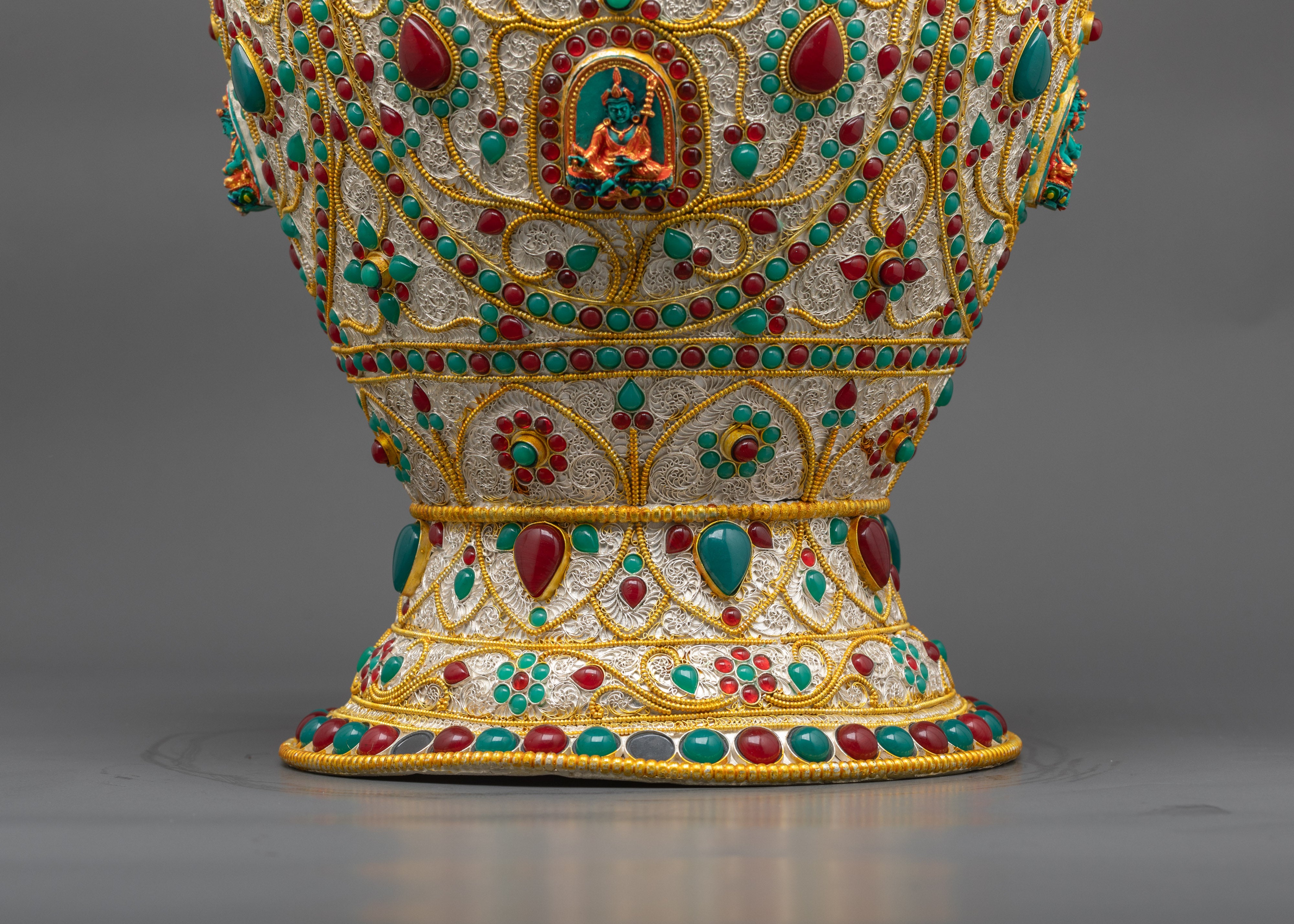 Close up of Tibetan rice pot showing Dzambhala carving with ruby turquoise emerald gems