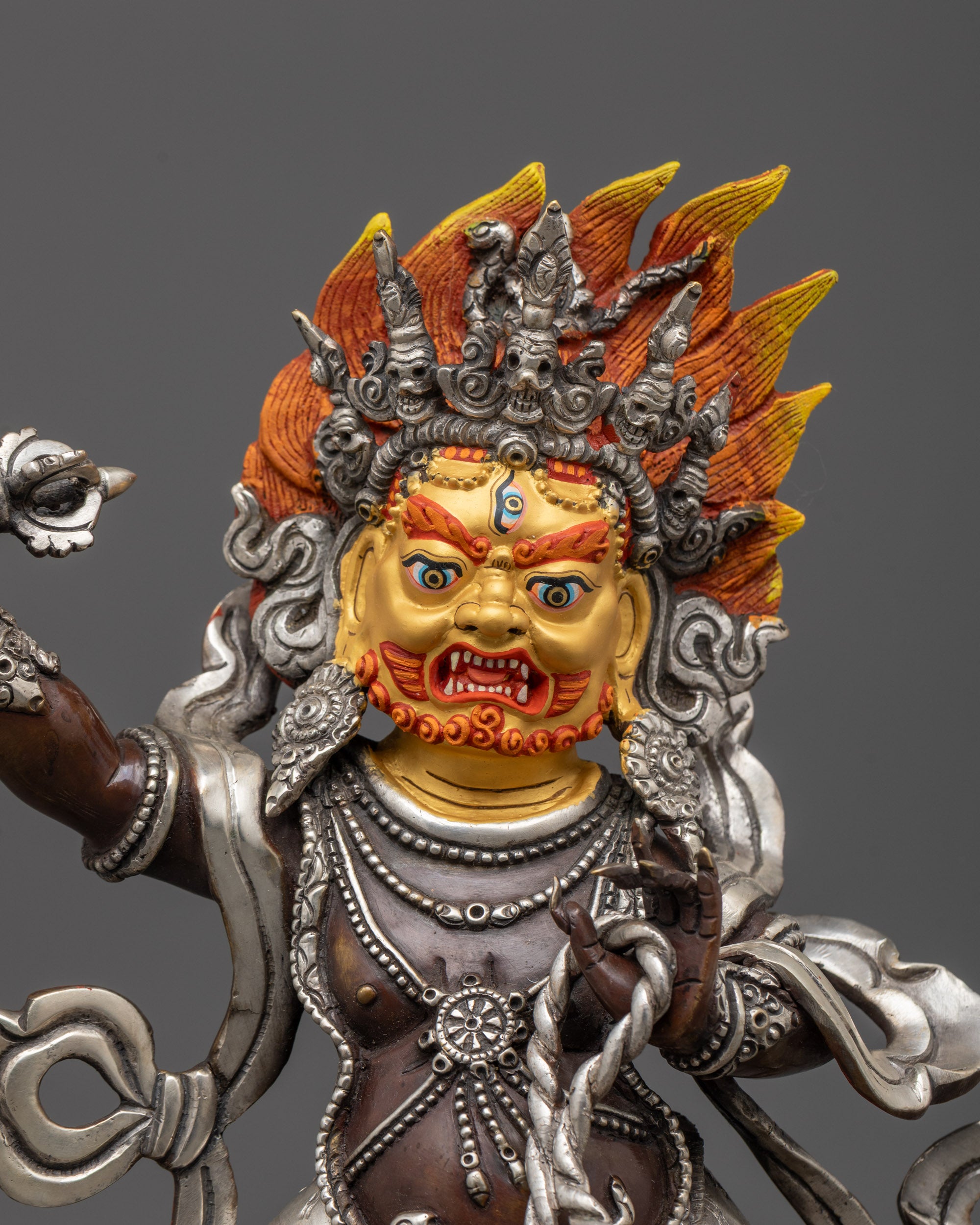Close up of Vajrapani’s skull crown, finely carved jewelry, and gold-gilded face details
