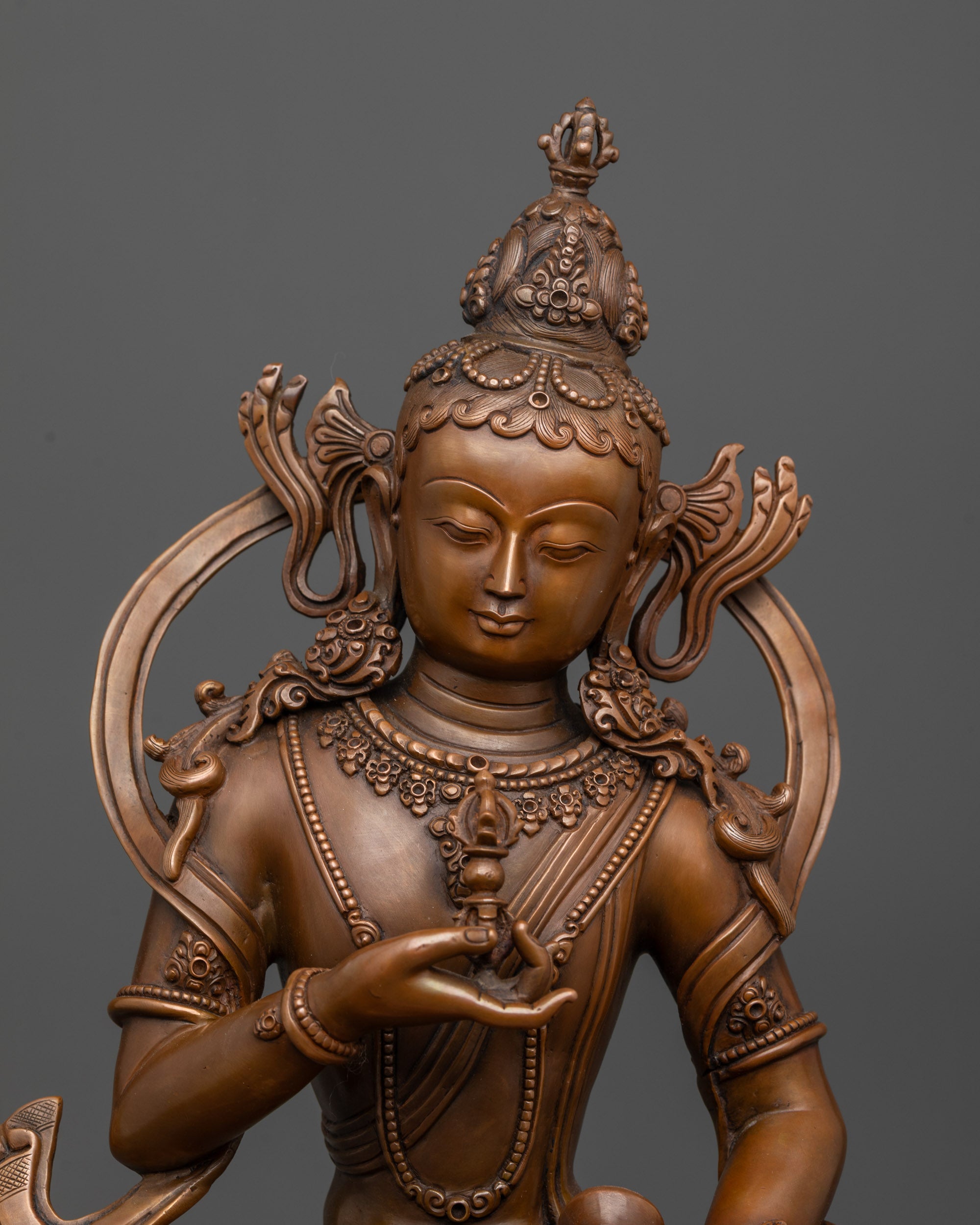 Close up of Vajrasattva Statue serene face and detailed oxidized copper robe