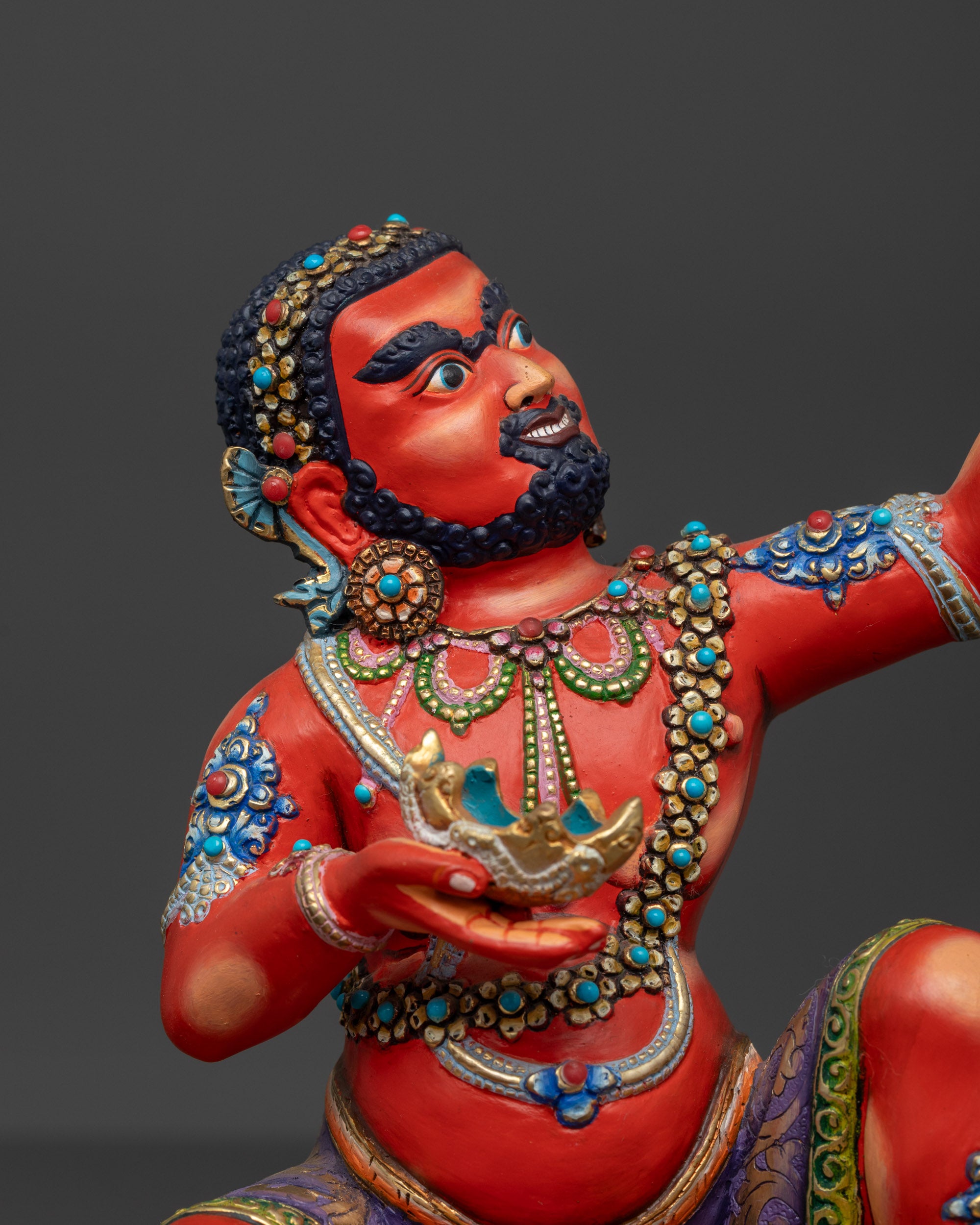 Close up of Virupa Statue showing red body, multi-colored jewelry, and semi-precious stones