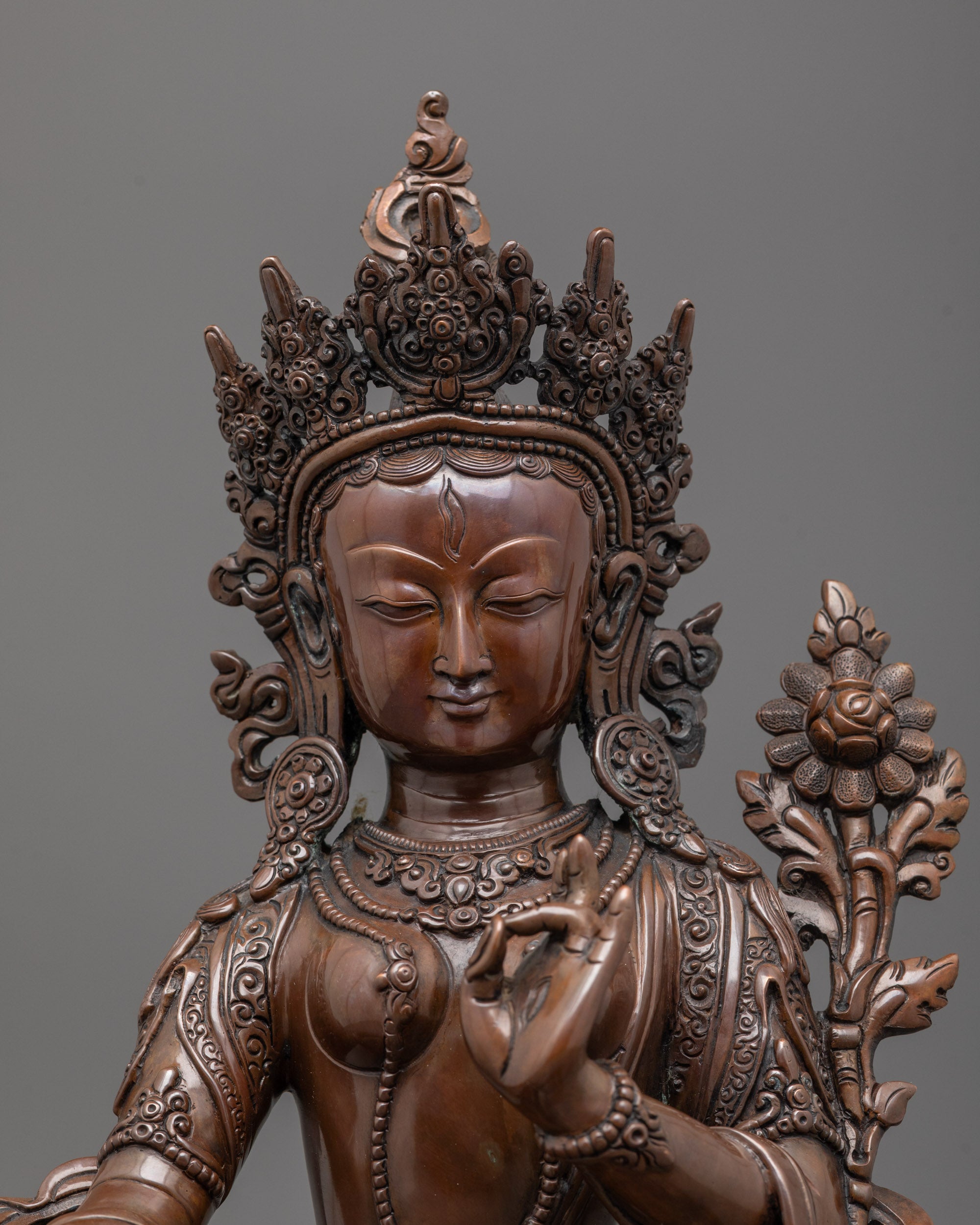 Close up of White Tara’s five-jeweled crown and seven carved eyes on oxidized copper statue