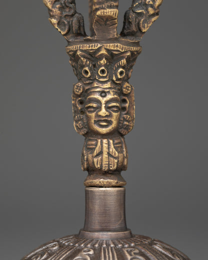 Close up of bell with deity handle and intricate bronze patterns for sacred rituals