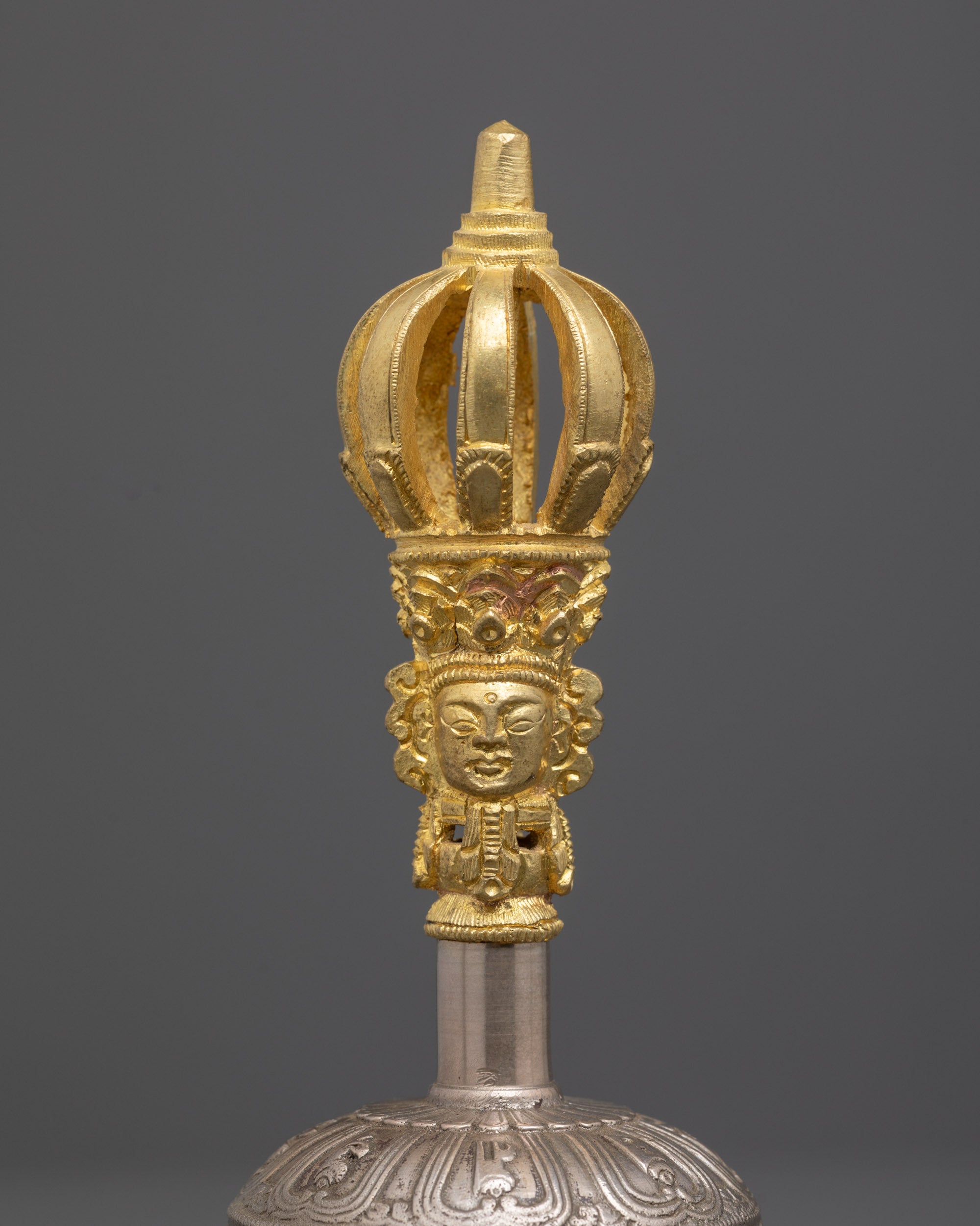 Close up of bronze bell handle with hand-carved sacred deity and symbolic patterns