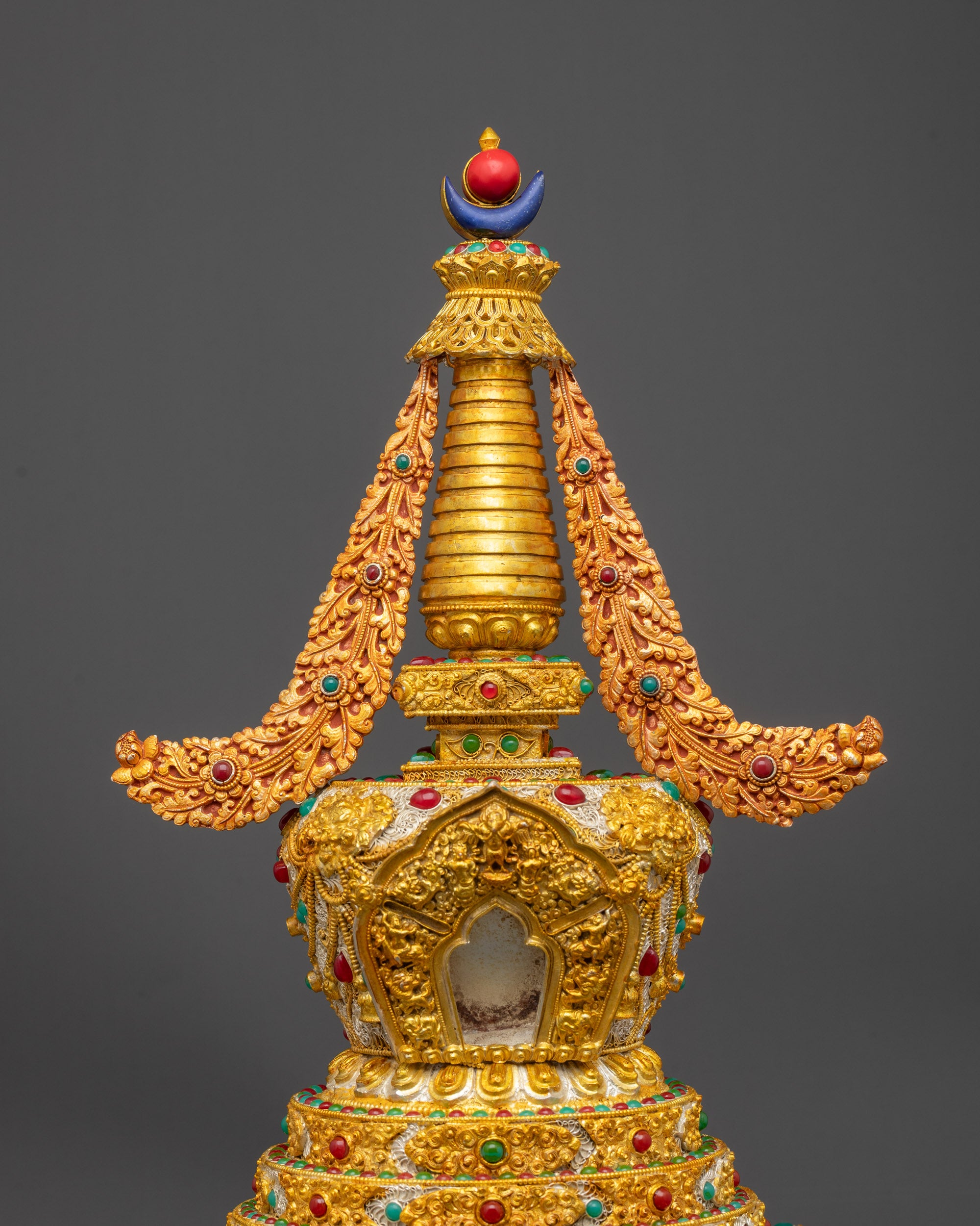 Close up of carved deities and semi-precious stones on Tibetan Golden Stupa

