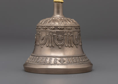 Close‑up of carved deity on gold‑plated bell handle and sacred symbols on copper dorje from handcrafted Buddhist ritual set