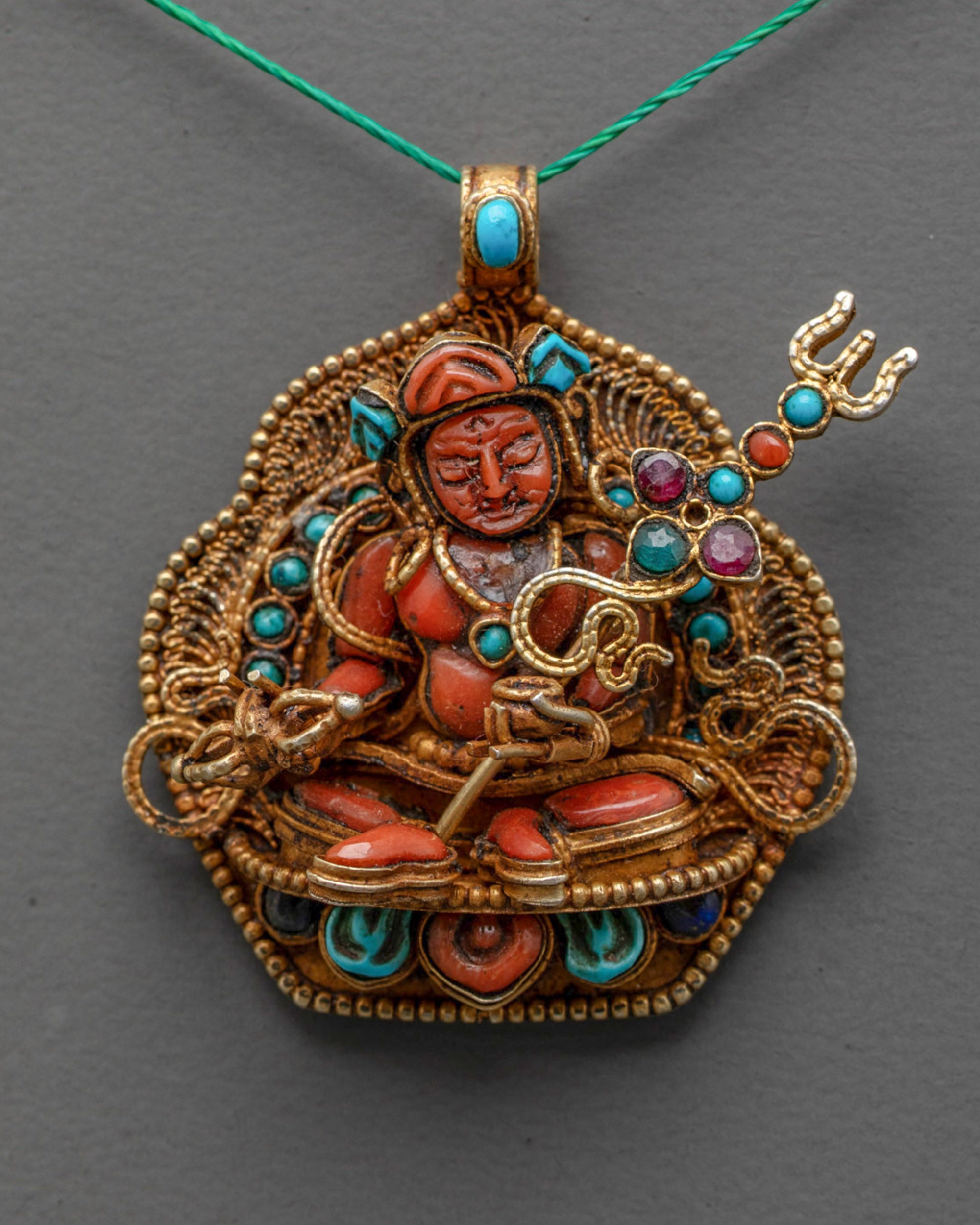Close up of coral Guru Rinpoche holding trident and vajra with semi-precious stones 