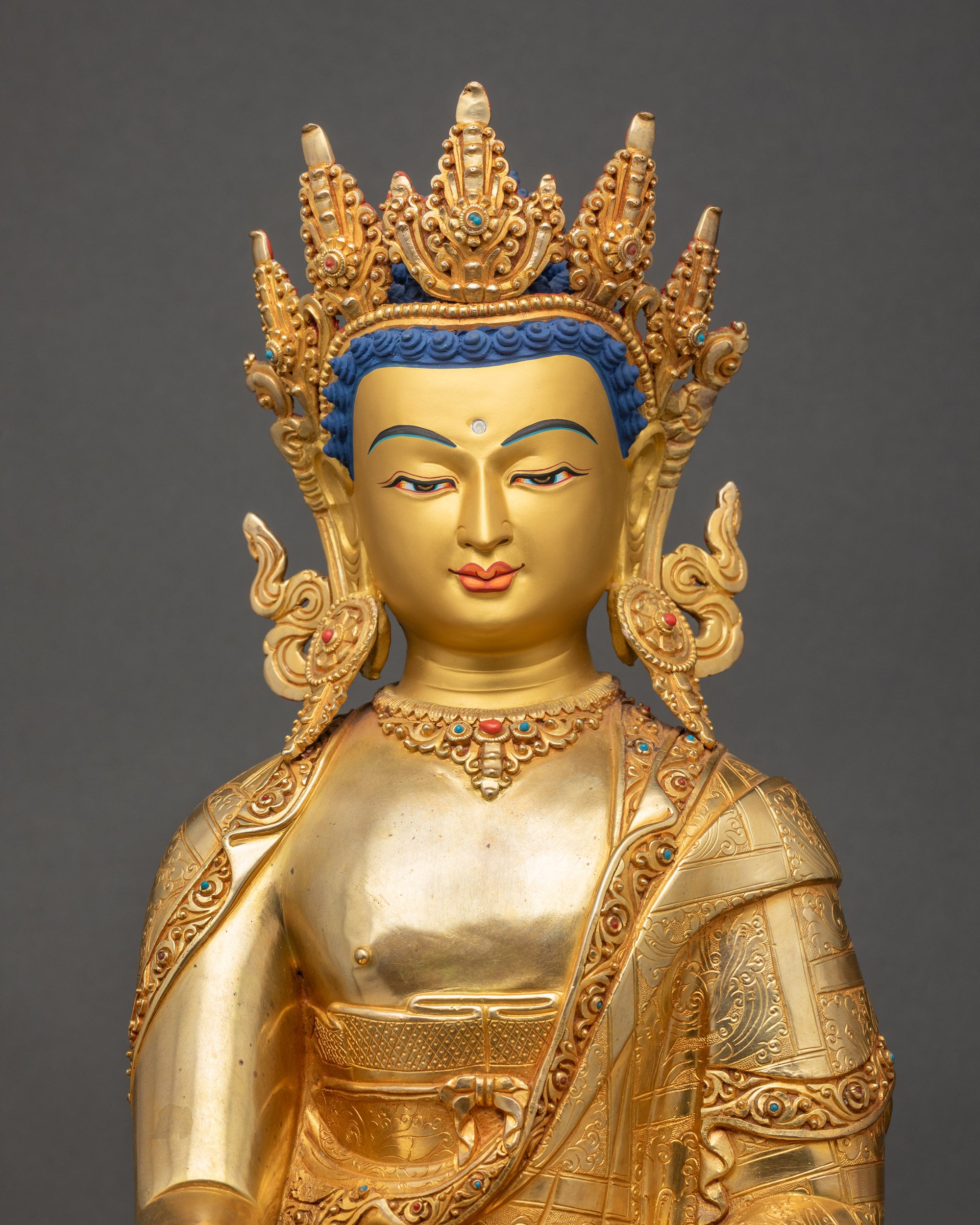 Close up of crowned Shakyamuni Buddha face showing calm expression and metal detailing