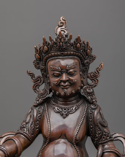 Close up of fierce oxidized copper face and intricate carved patterns on robes of Dzambhala