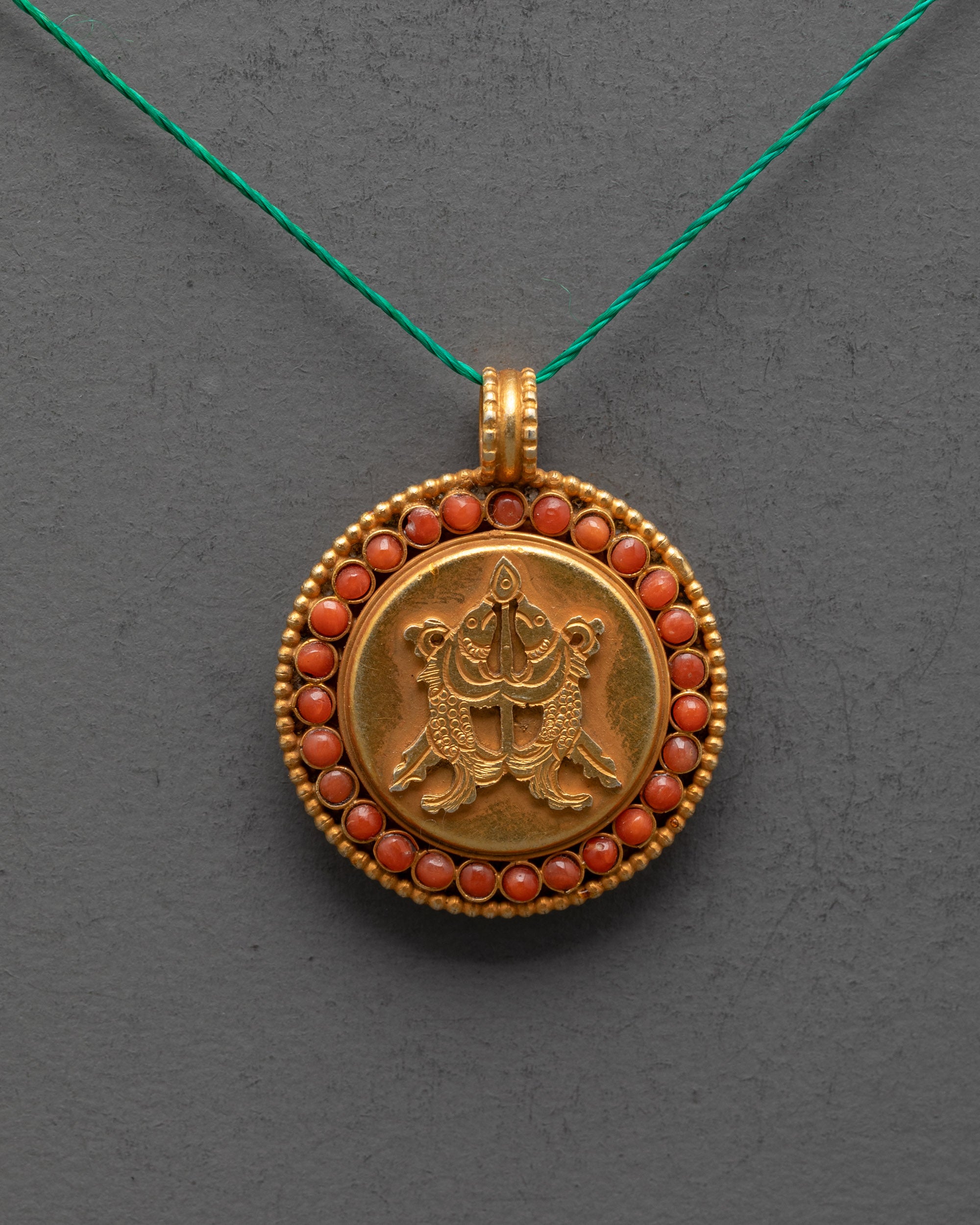 Close up of intricate golden fish carving on gold-plated copper locket from Patan, Nepal