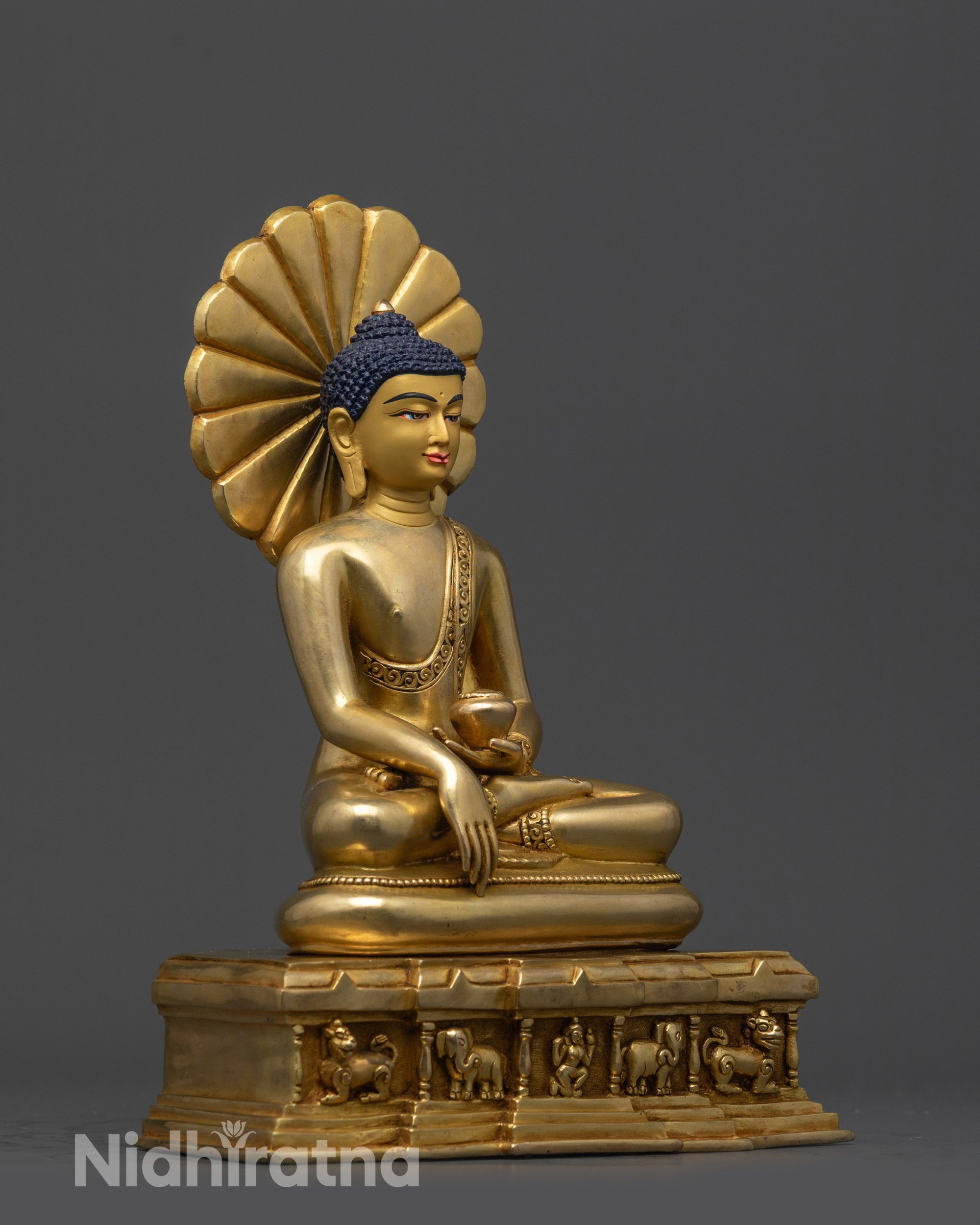 Close up of intricate monk’s robe and majestic halo on gold fire-gilded Shakyamuni Buddha