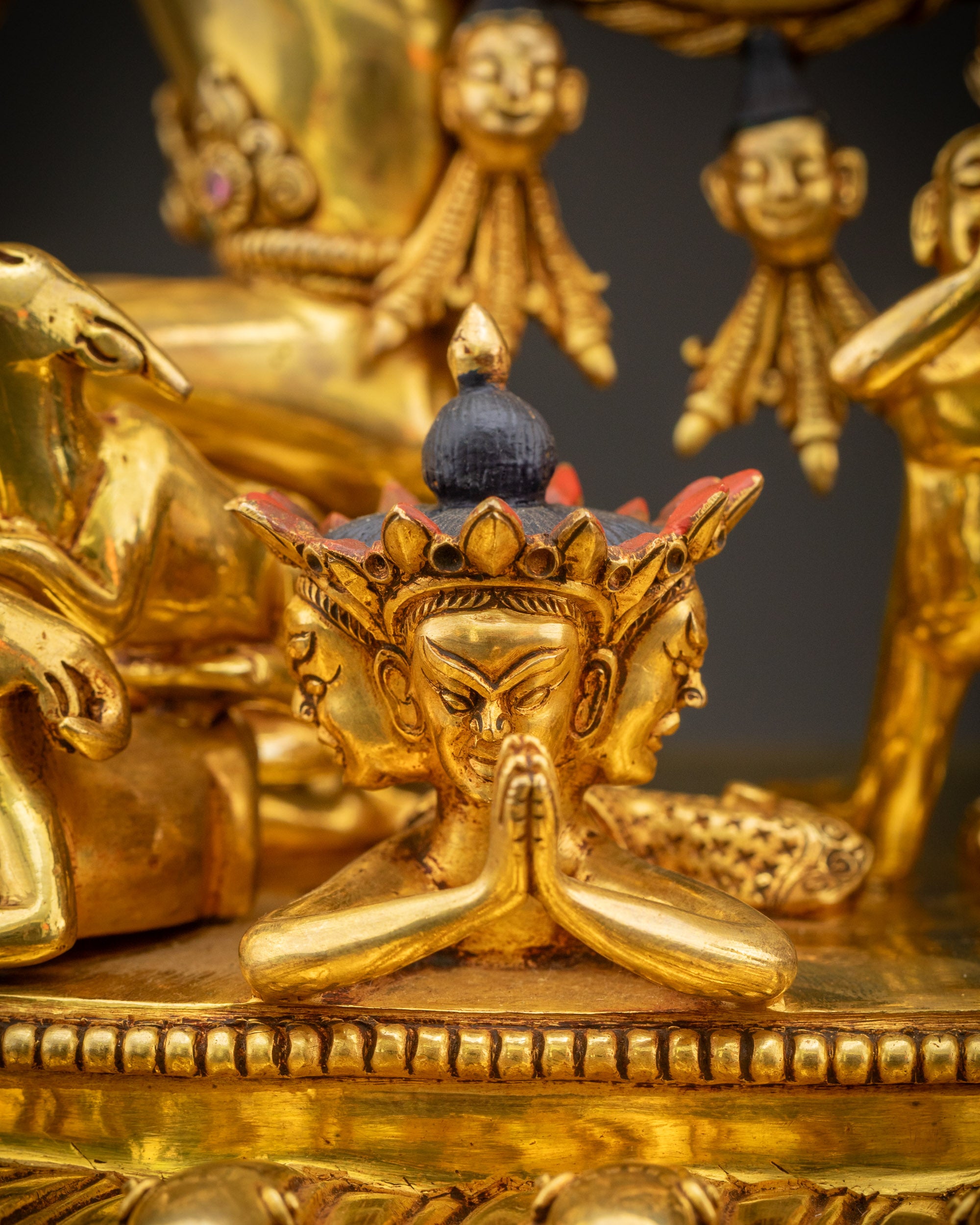 Close up of miniature celestial and subjugated figures on lotus base with intricate high-relief gold carvings