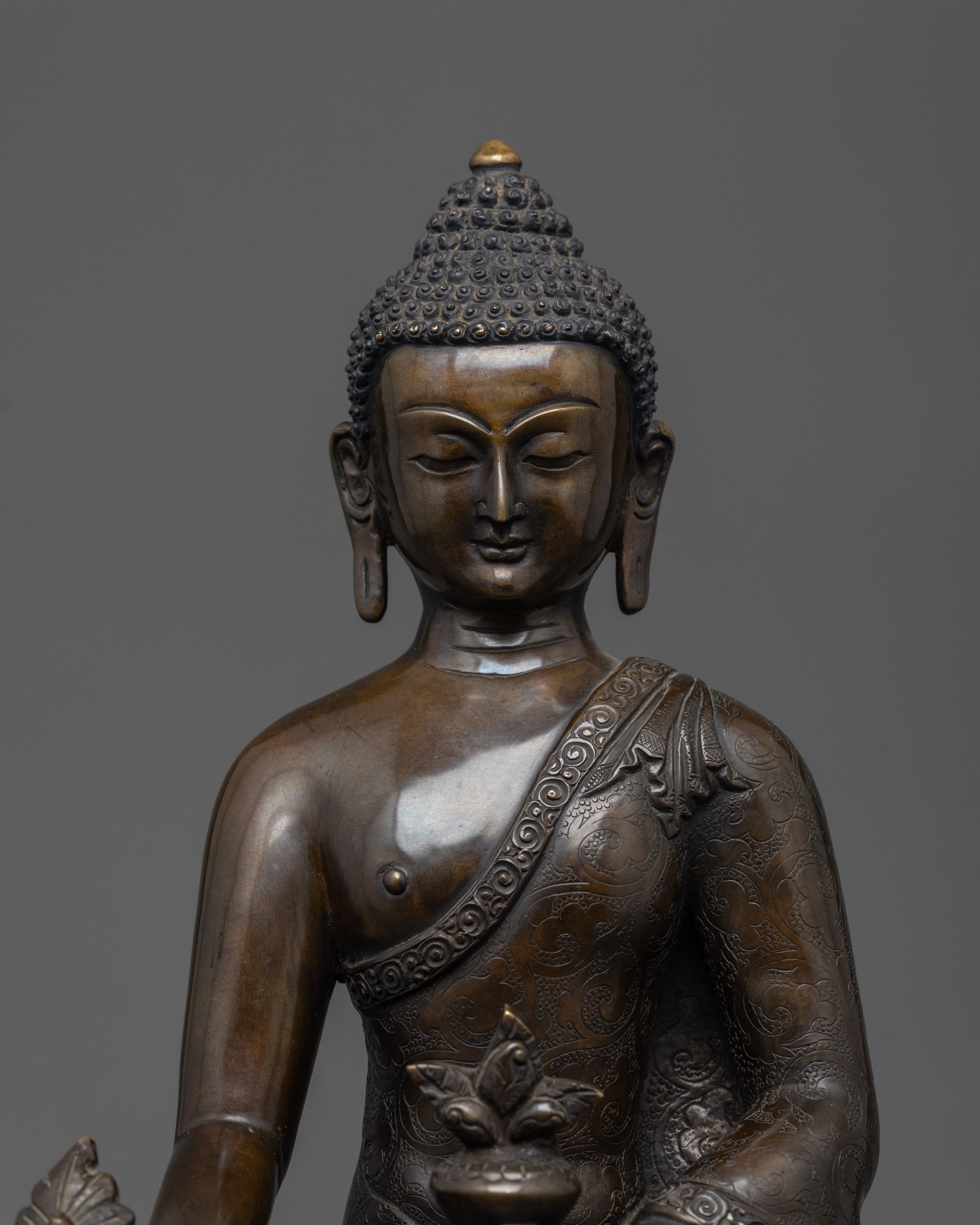 Close up of oxidized copper Bhaisajyaguru Buddha showing intricate robe patterns