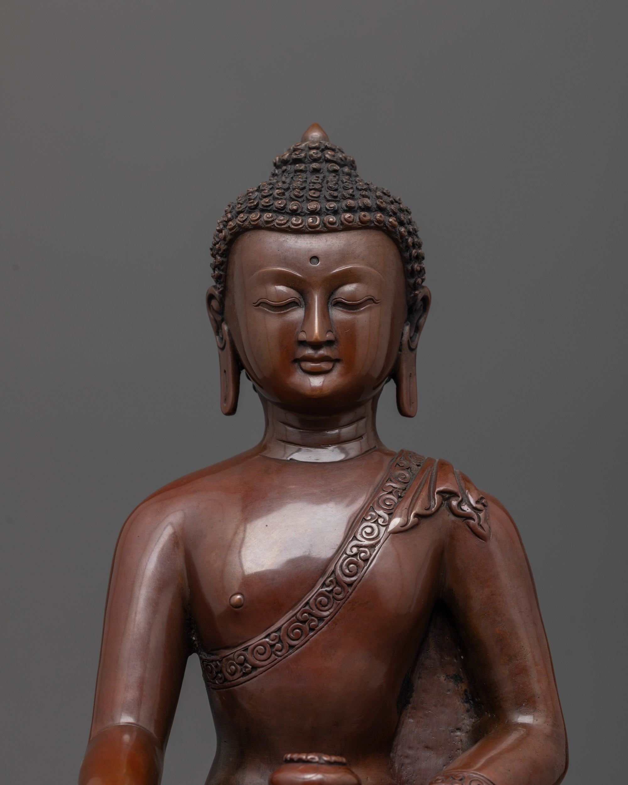Close up of oxidized copper Buddha statue holding alms bowl with earth-touching mudra
