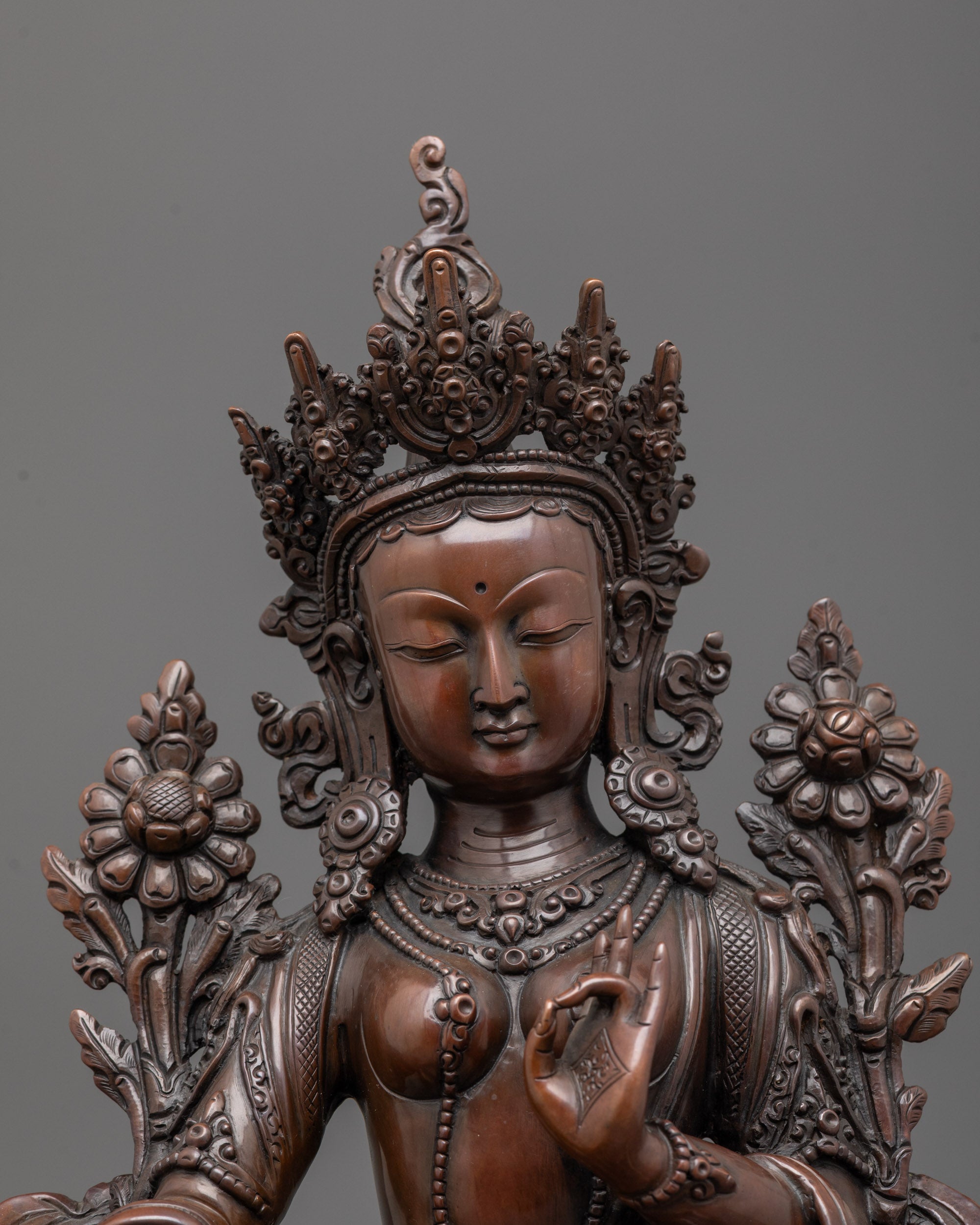 Close up of oxidized copper face and five-jeweled crown on Green Tara statue handcrafted art.