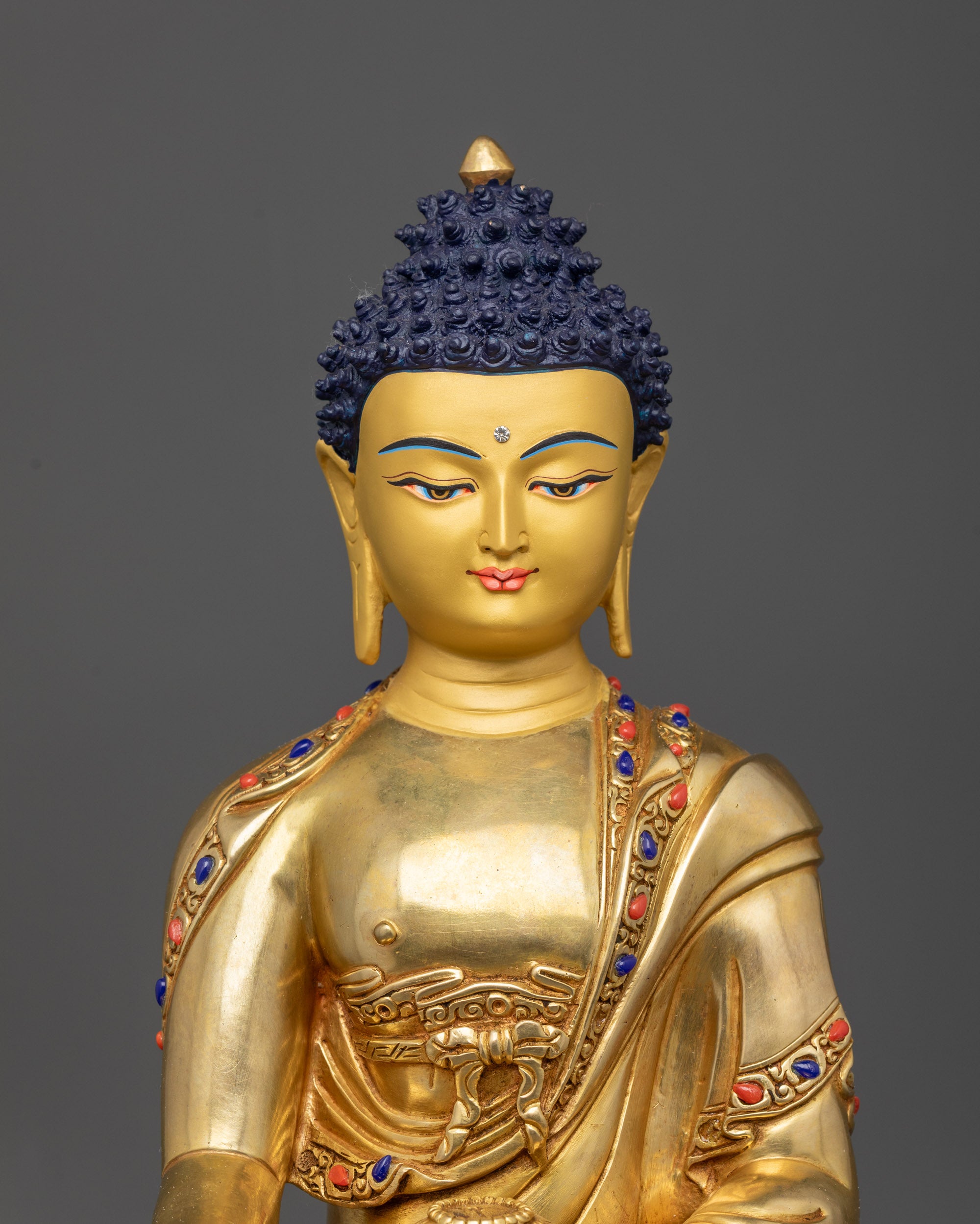 Close up of peaceful face and intricate monk’s robe on Shakyamuni Buddha statue
